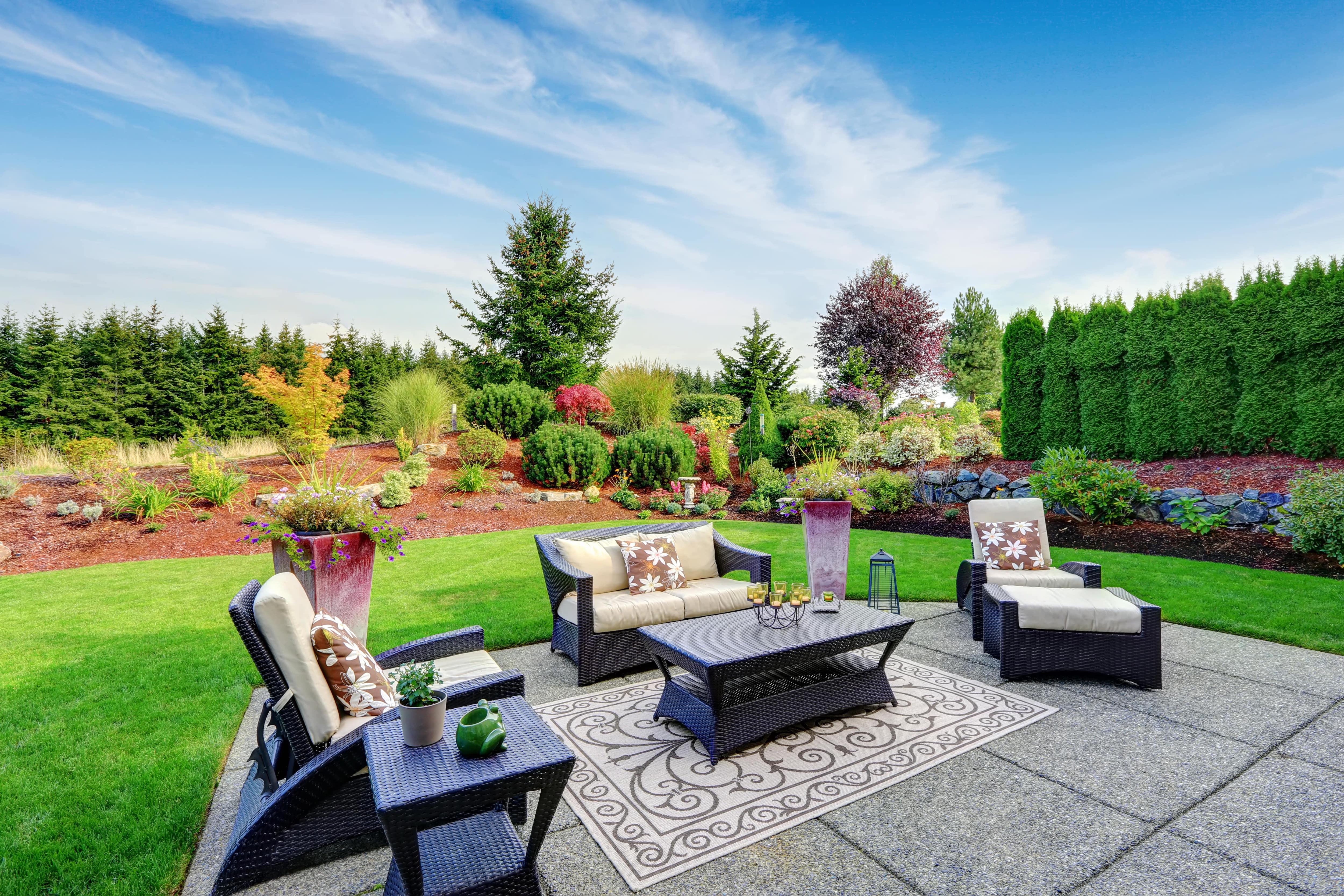 Backyard patio surrounded by a beautiful landscape design with layers of different plants