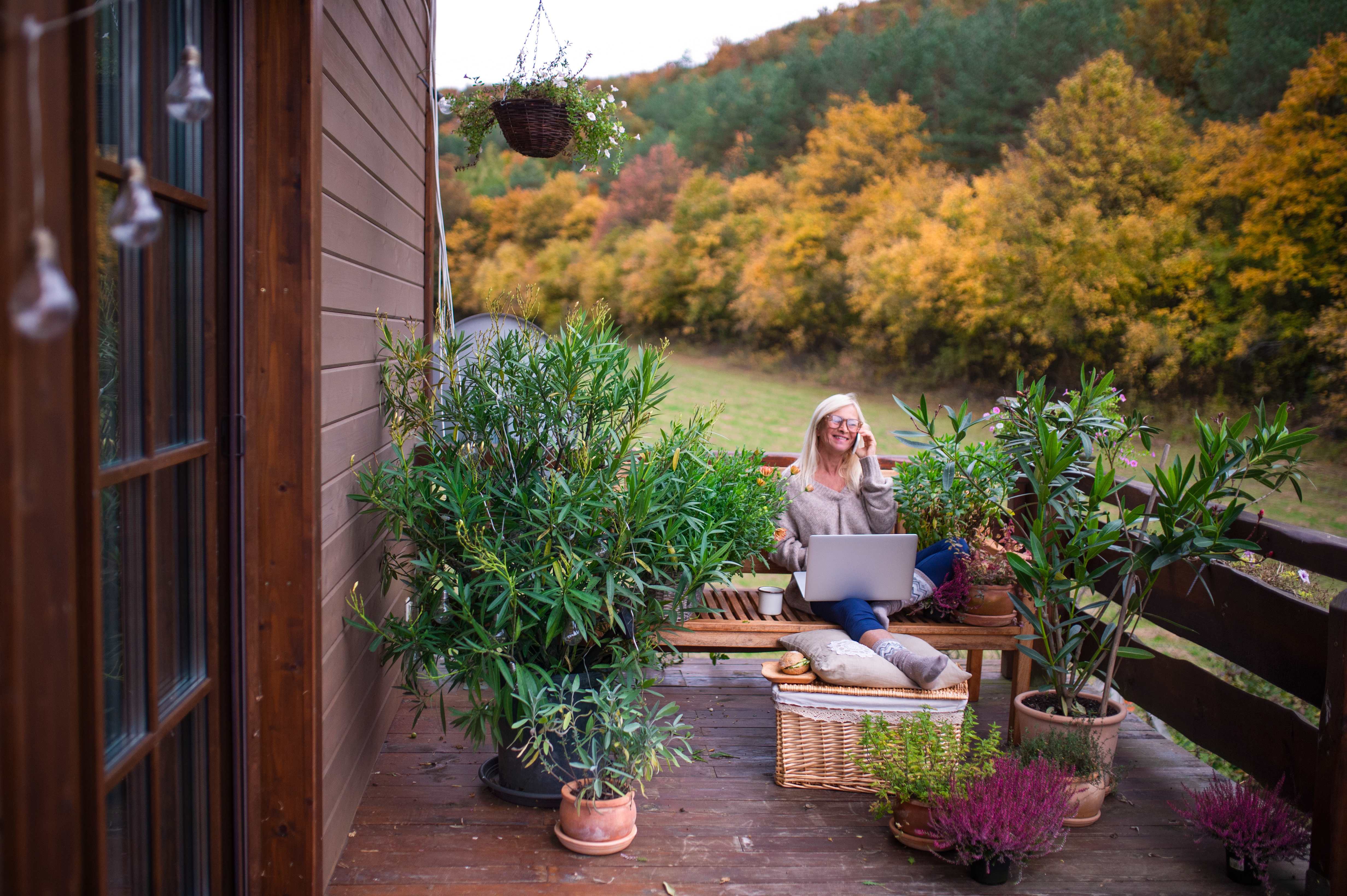 Woman sitting on her deck surrounded by potted plants