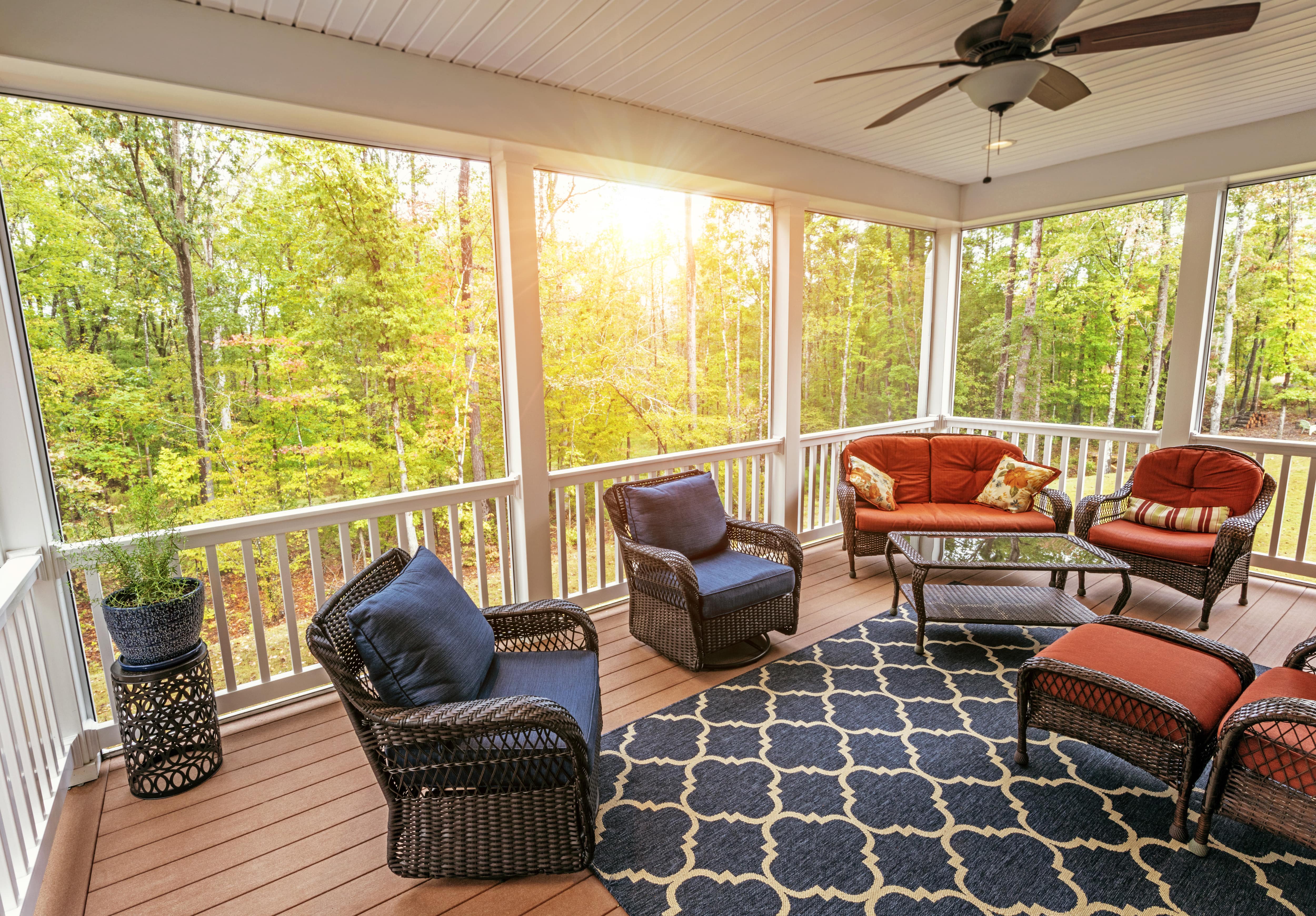 A screened-in porch with patio furniture set and a blue patterned area rug