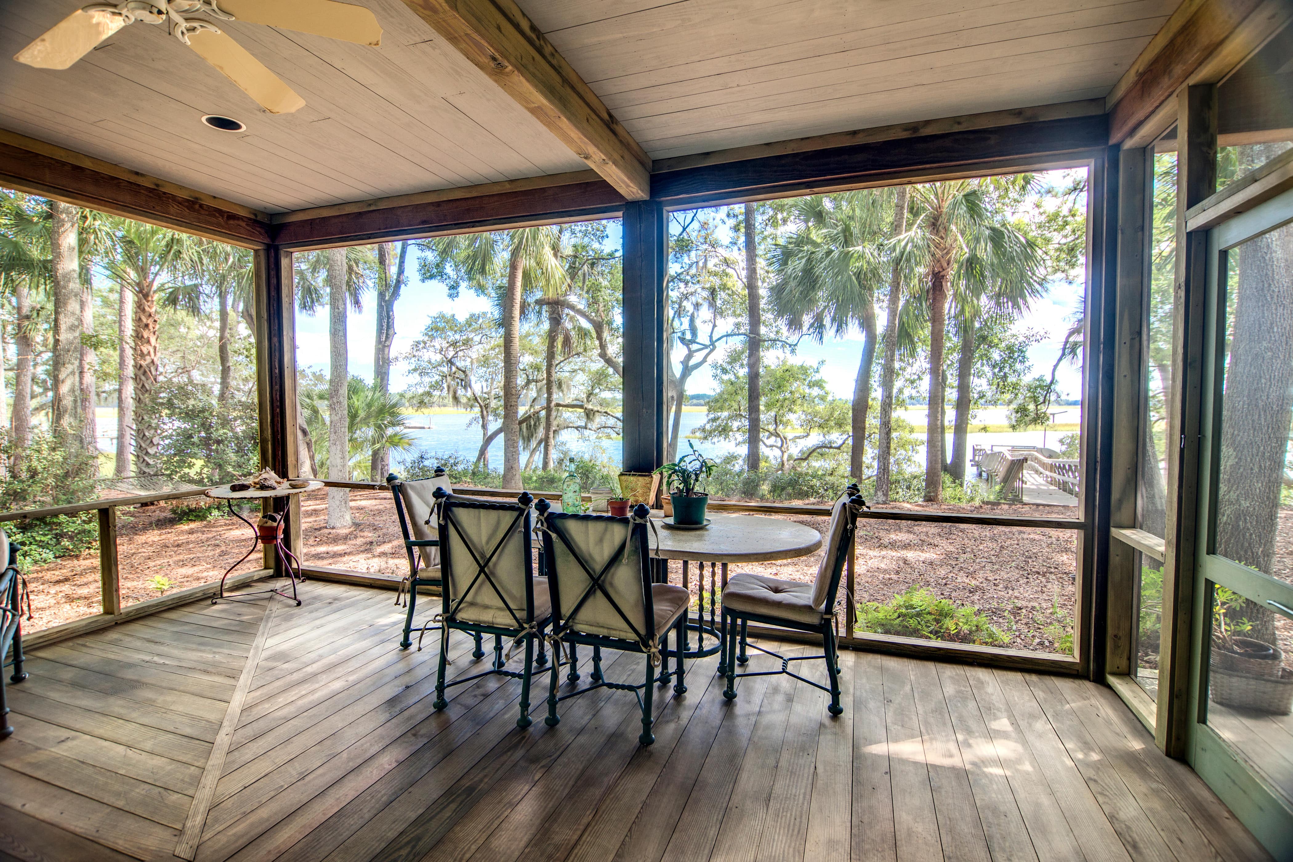 A simple screened-in porch with exposed beams, a patio set, and a tropical view