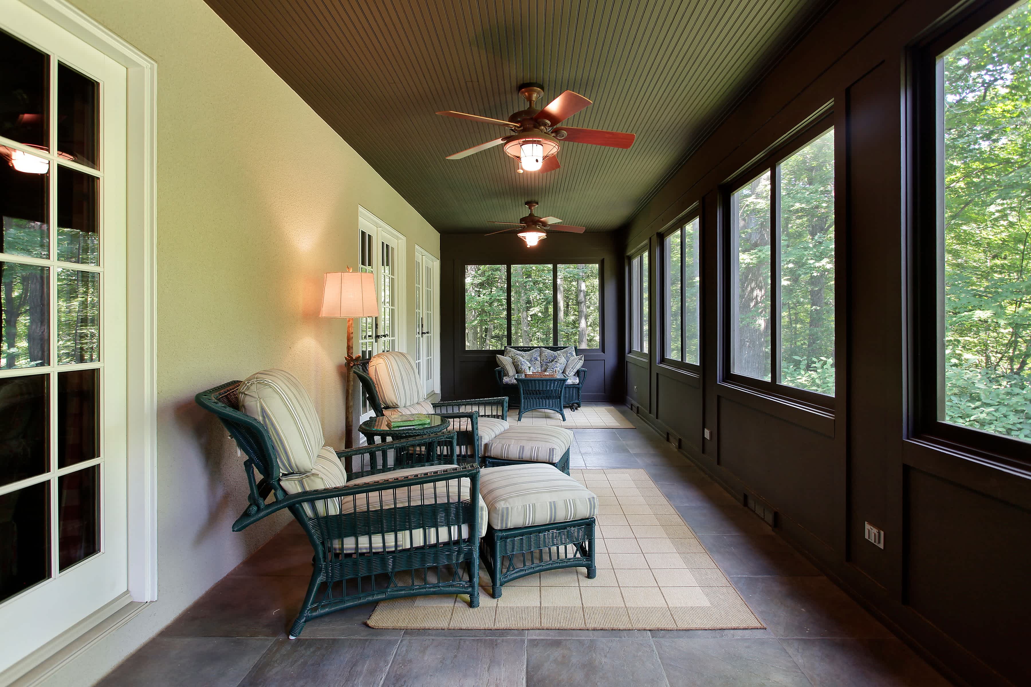 A screened-in porch with dark walls, a white accent wall, and a dark shiplap ceiling