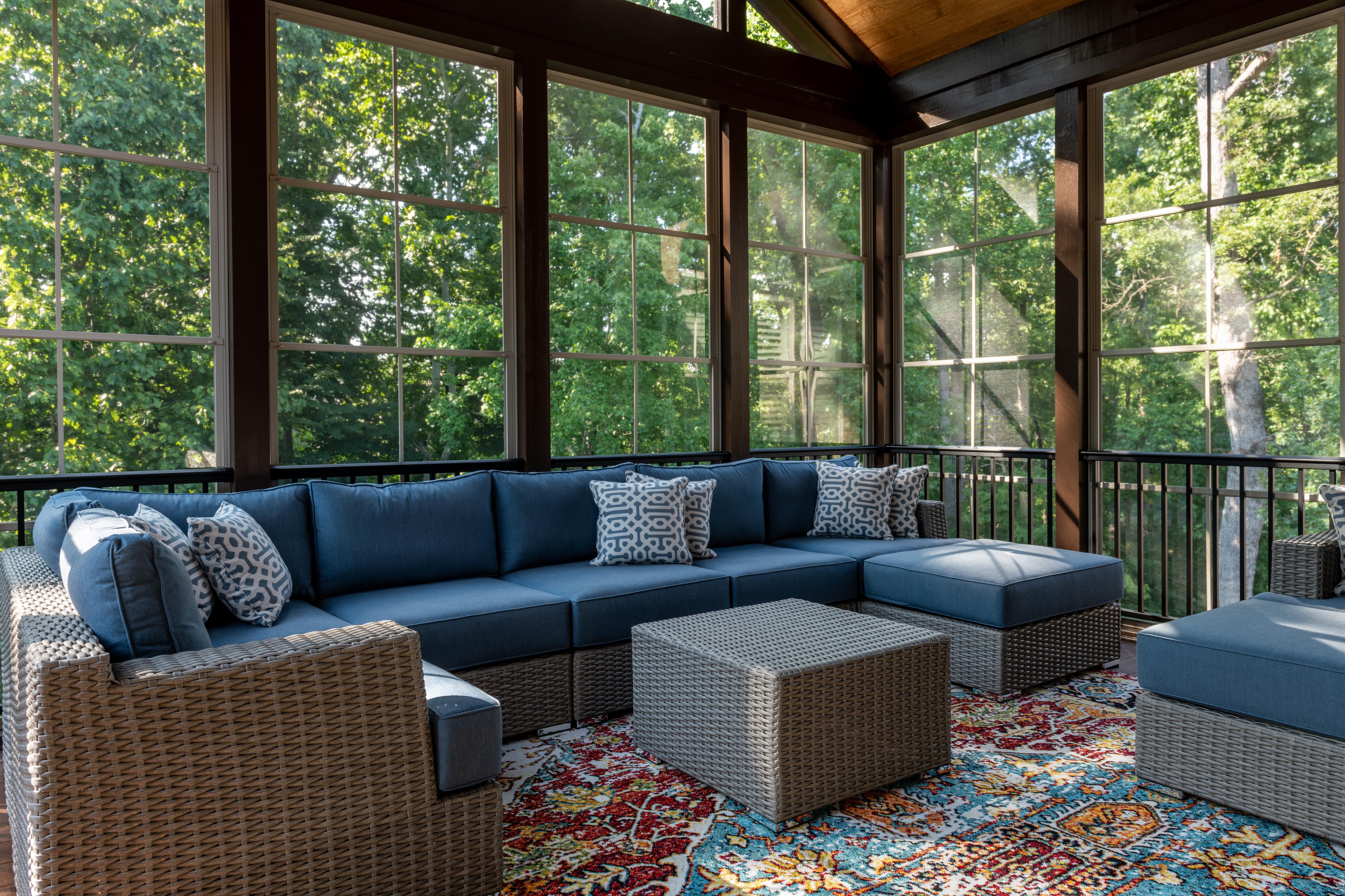 A screened-in porch with a large wicker sectional patio set