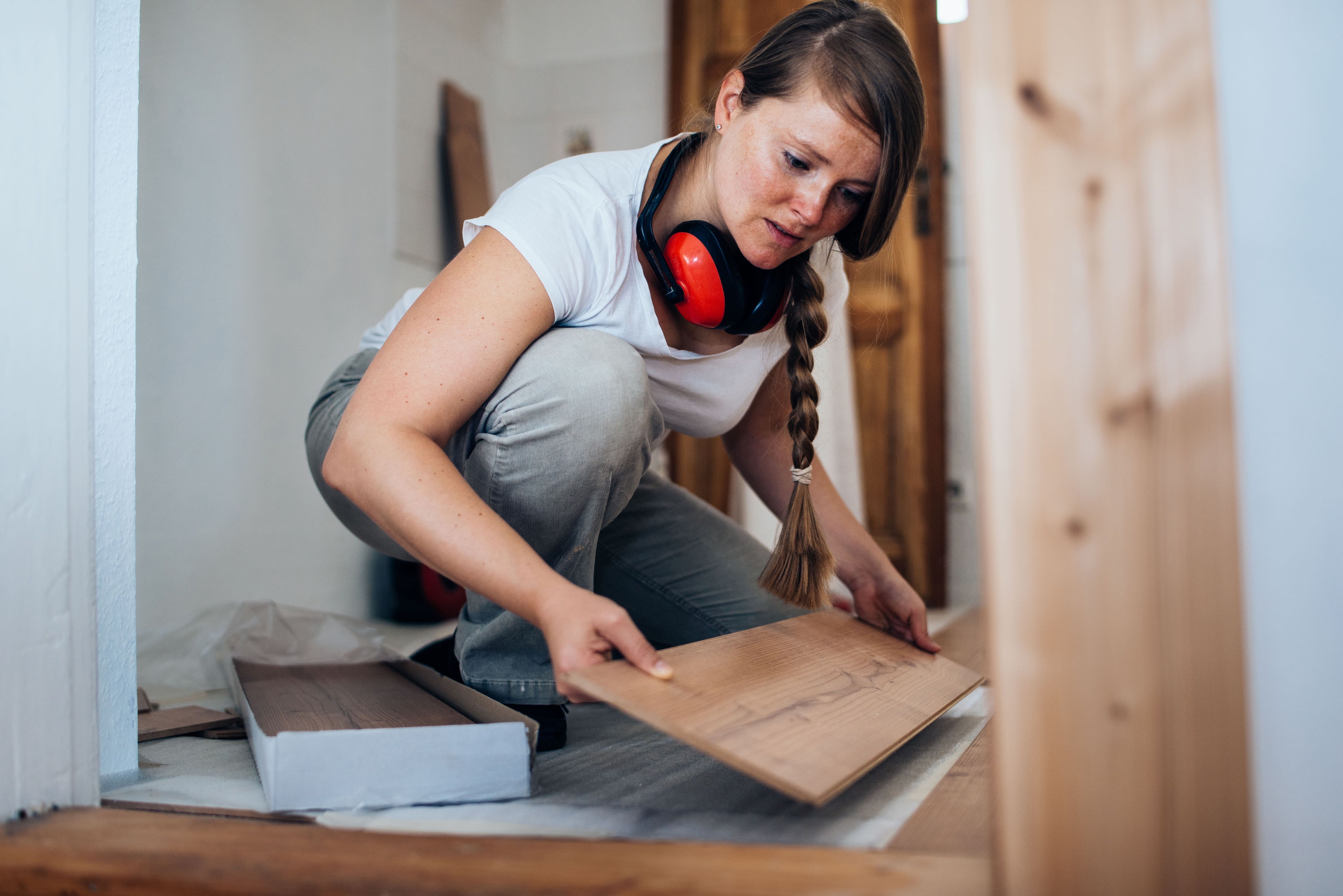 A woman installing laminate flooring