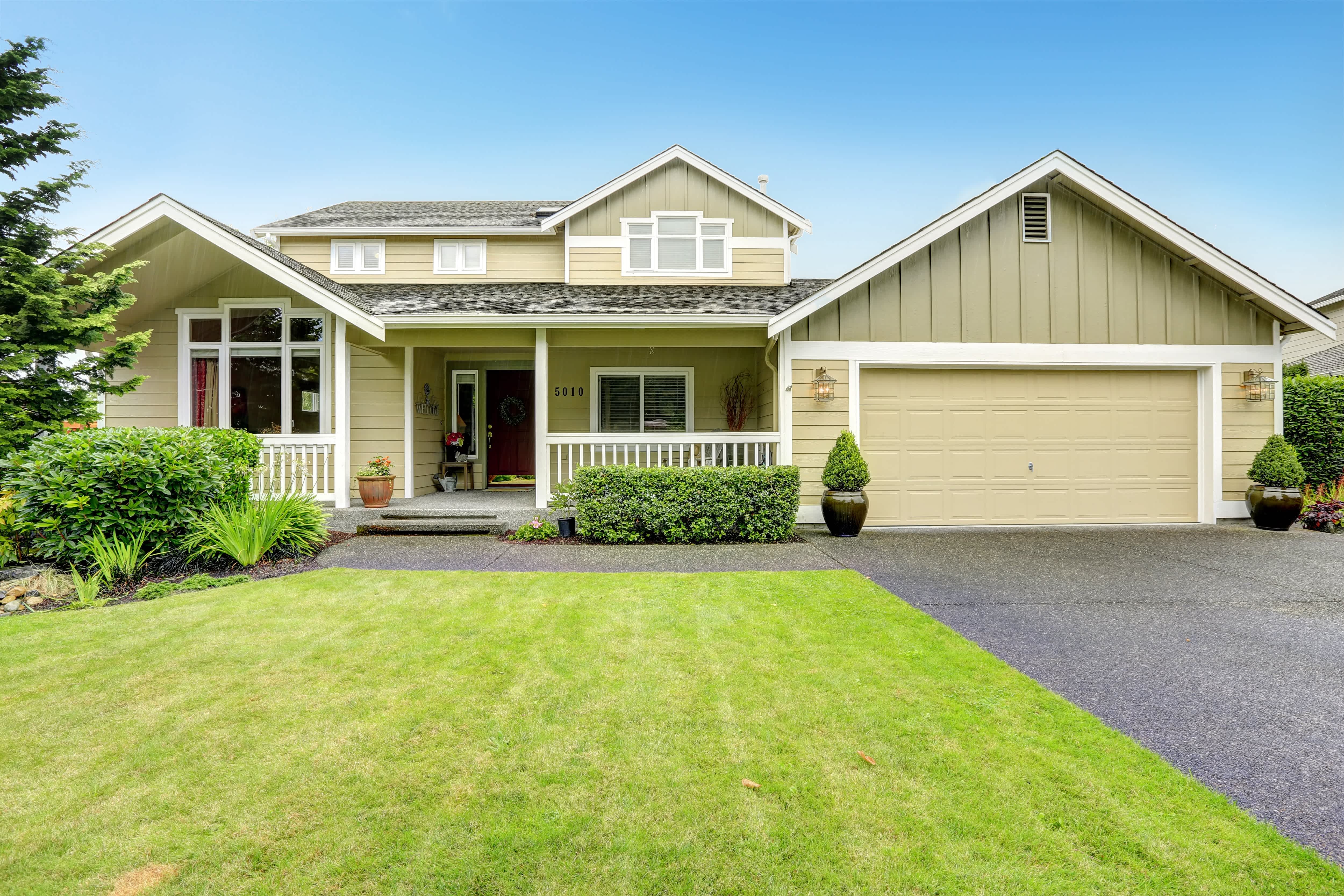 Tan house and trimmed green lawn