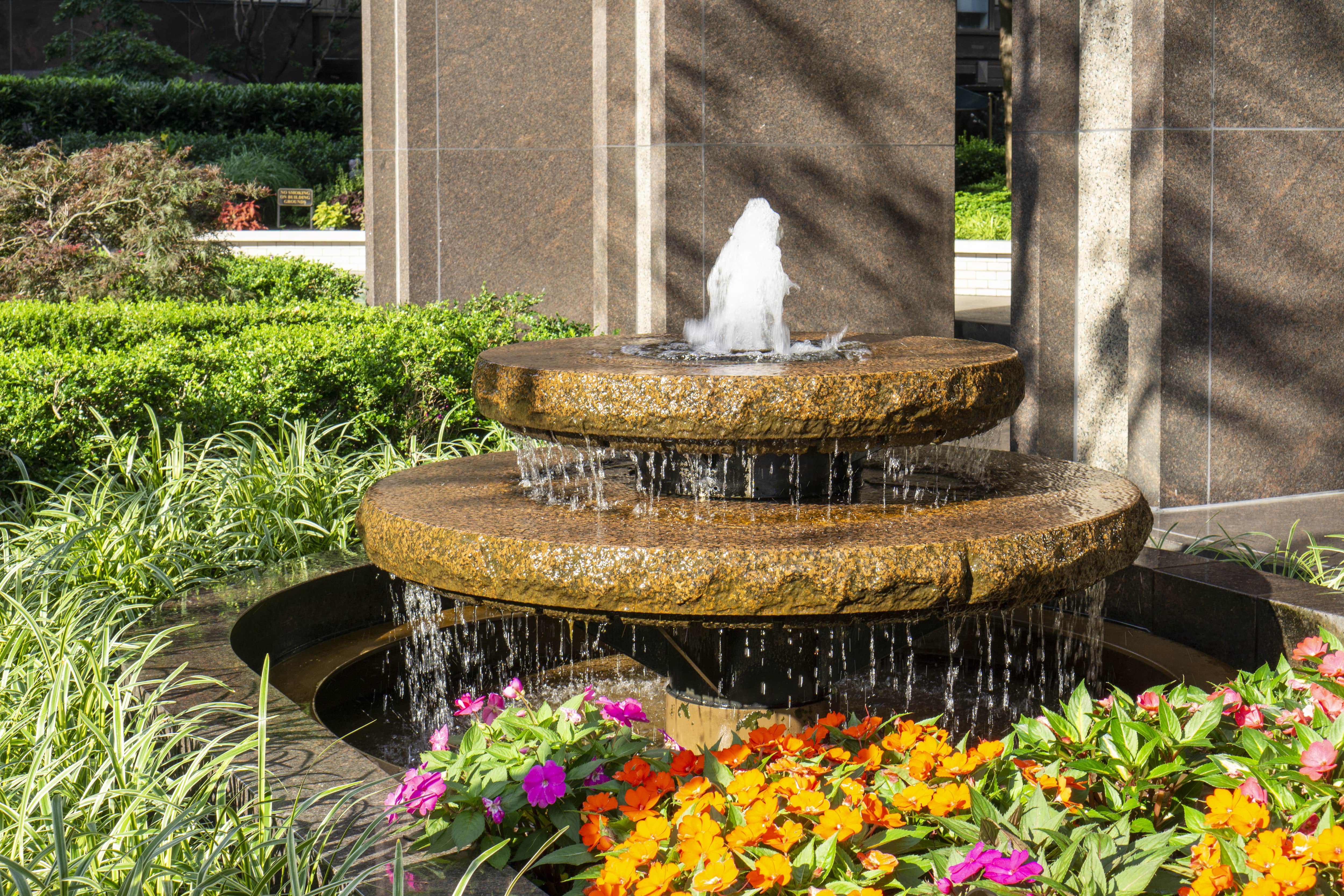 Water fountain surrounded by flowers and plants