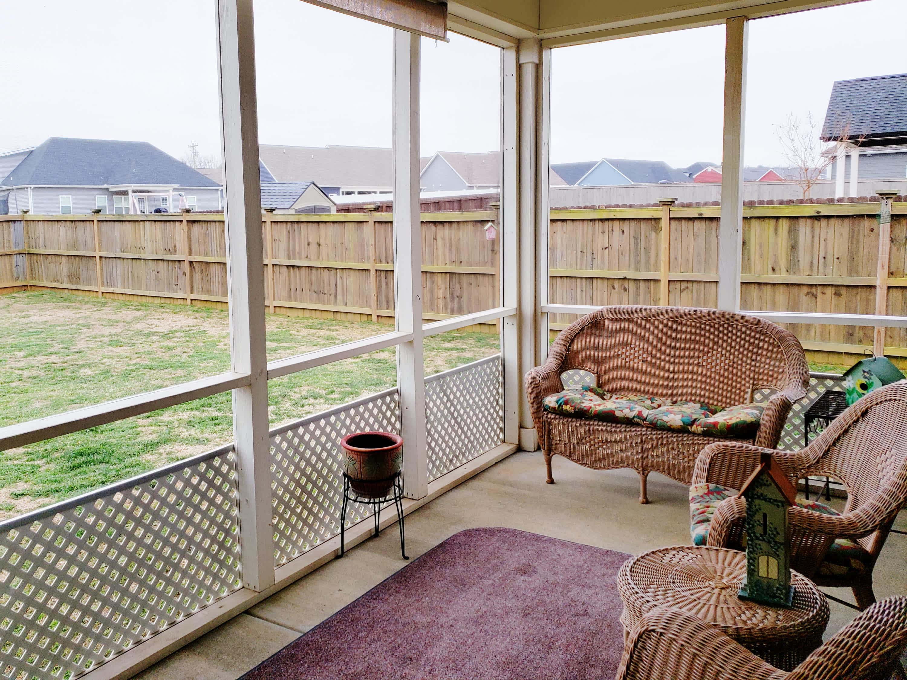 A small screened-in porch with a wicker furniture set