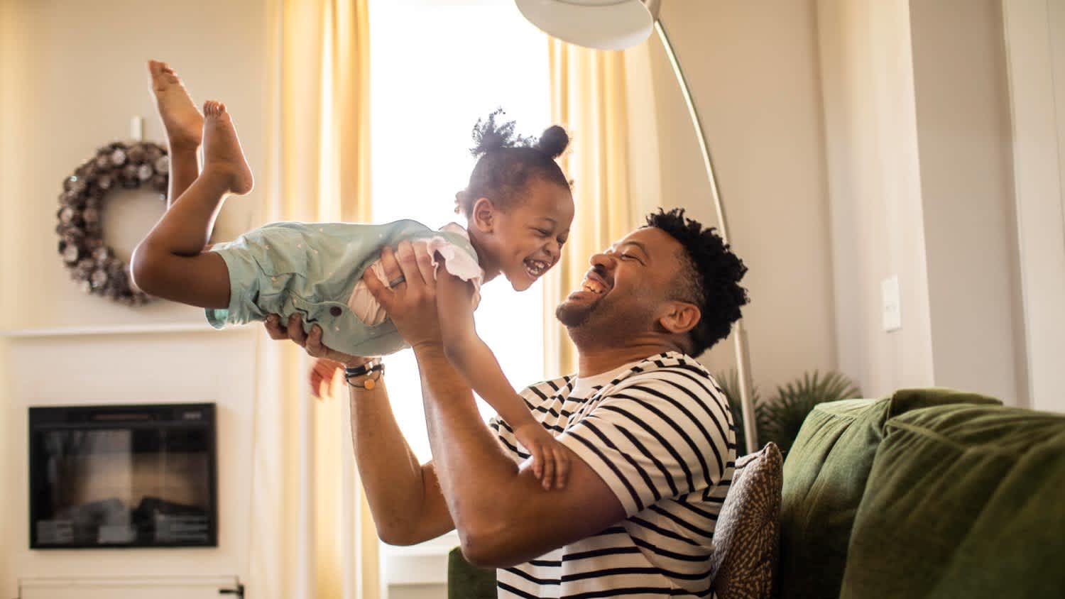 A father lifting toddler daughter in the air