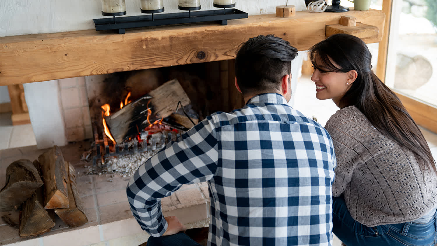 A couple burns logs in fireplace of cabin