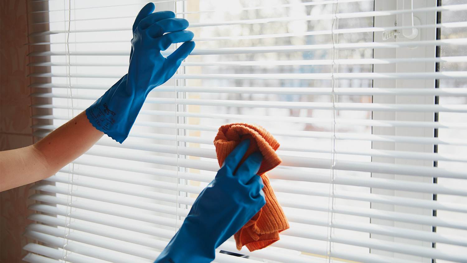 woman cleaning vertical blinds with rag