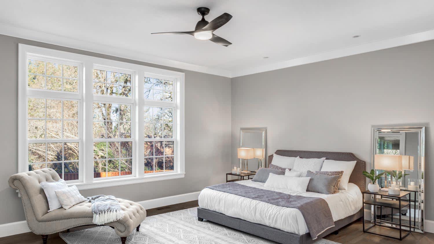 A bedroom with large windows and a fan