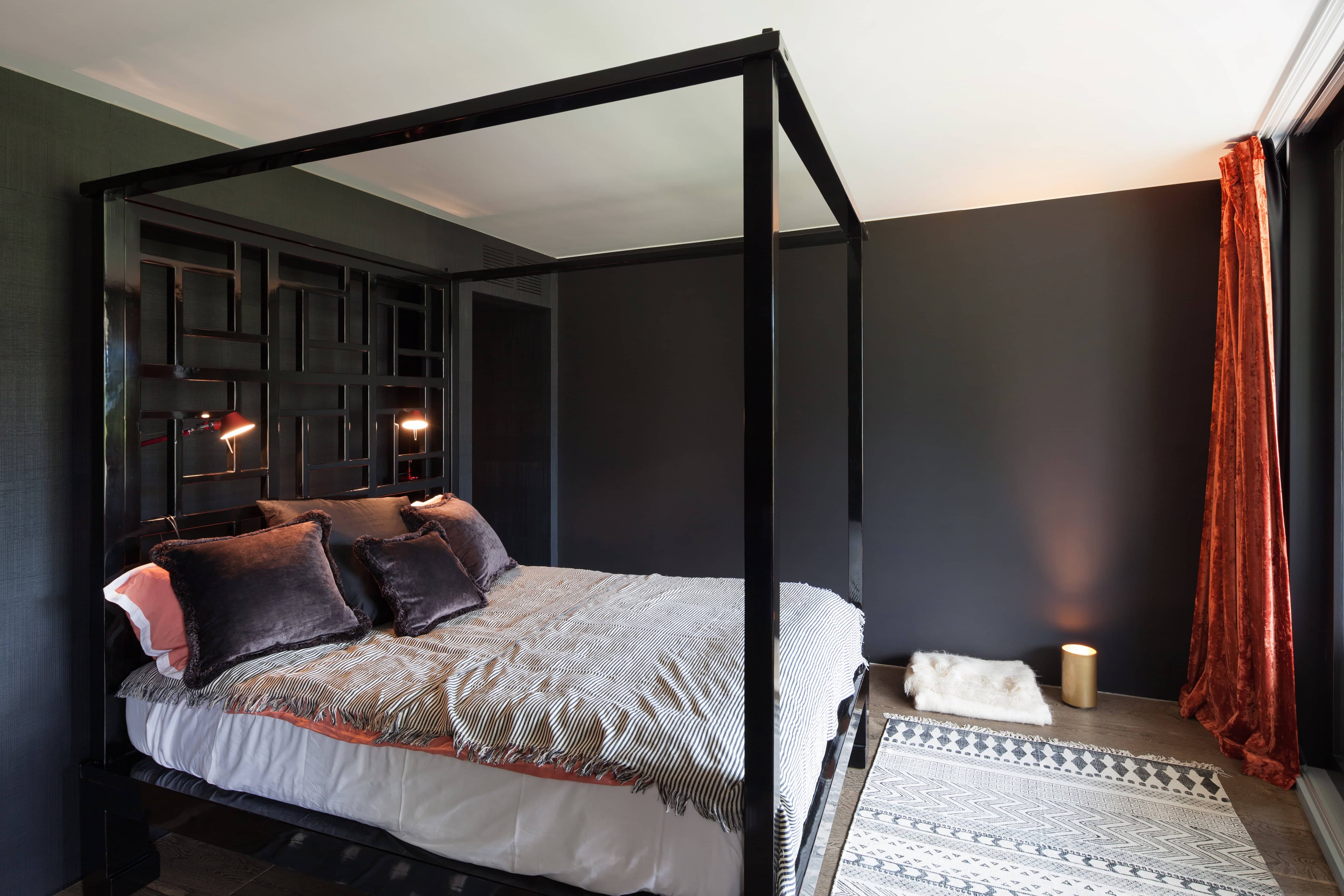 Dramatic dark modern bedroom with a bed that has a black canopy bed frame