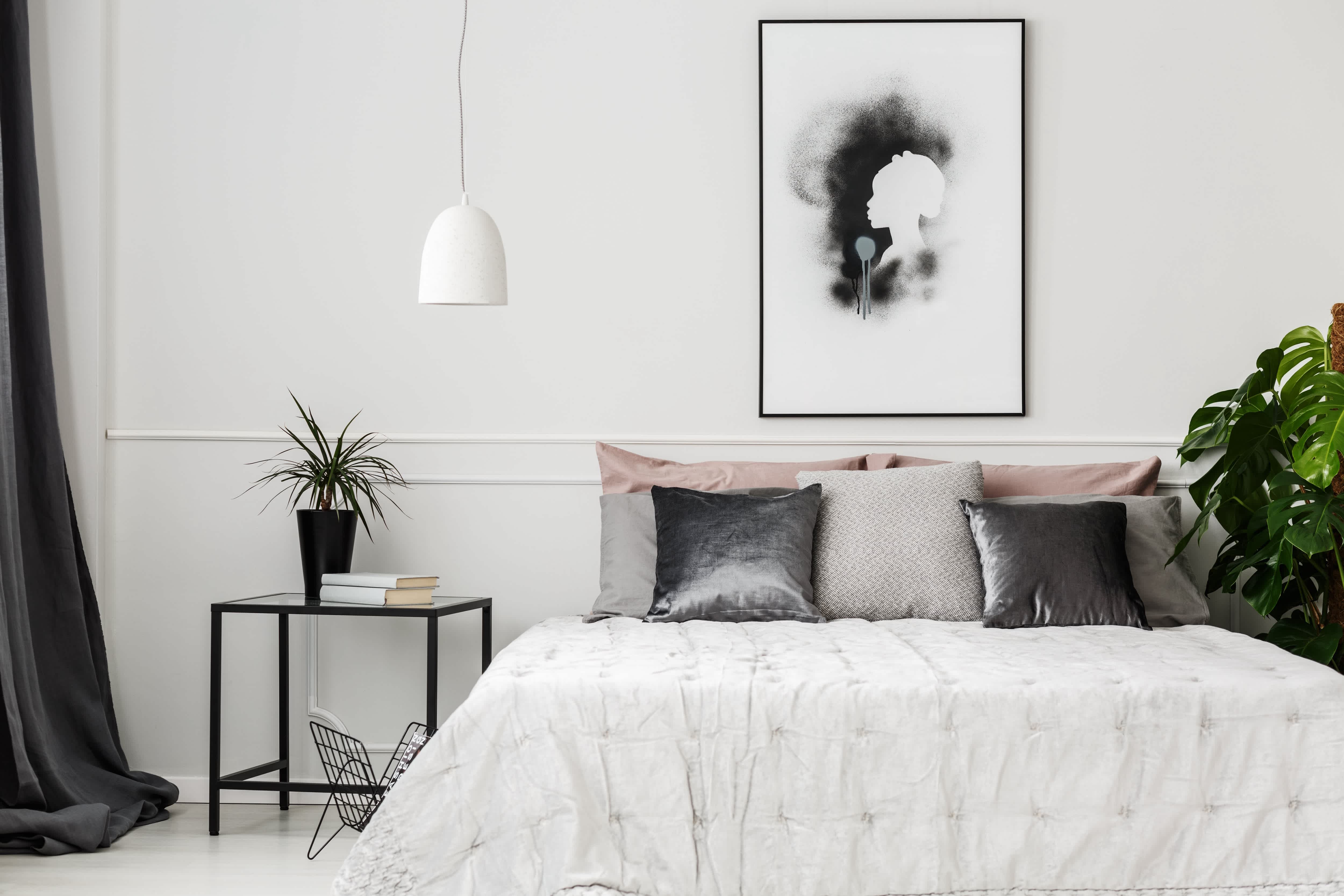 gray and white bedroom with large artwork hanging over bed