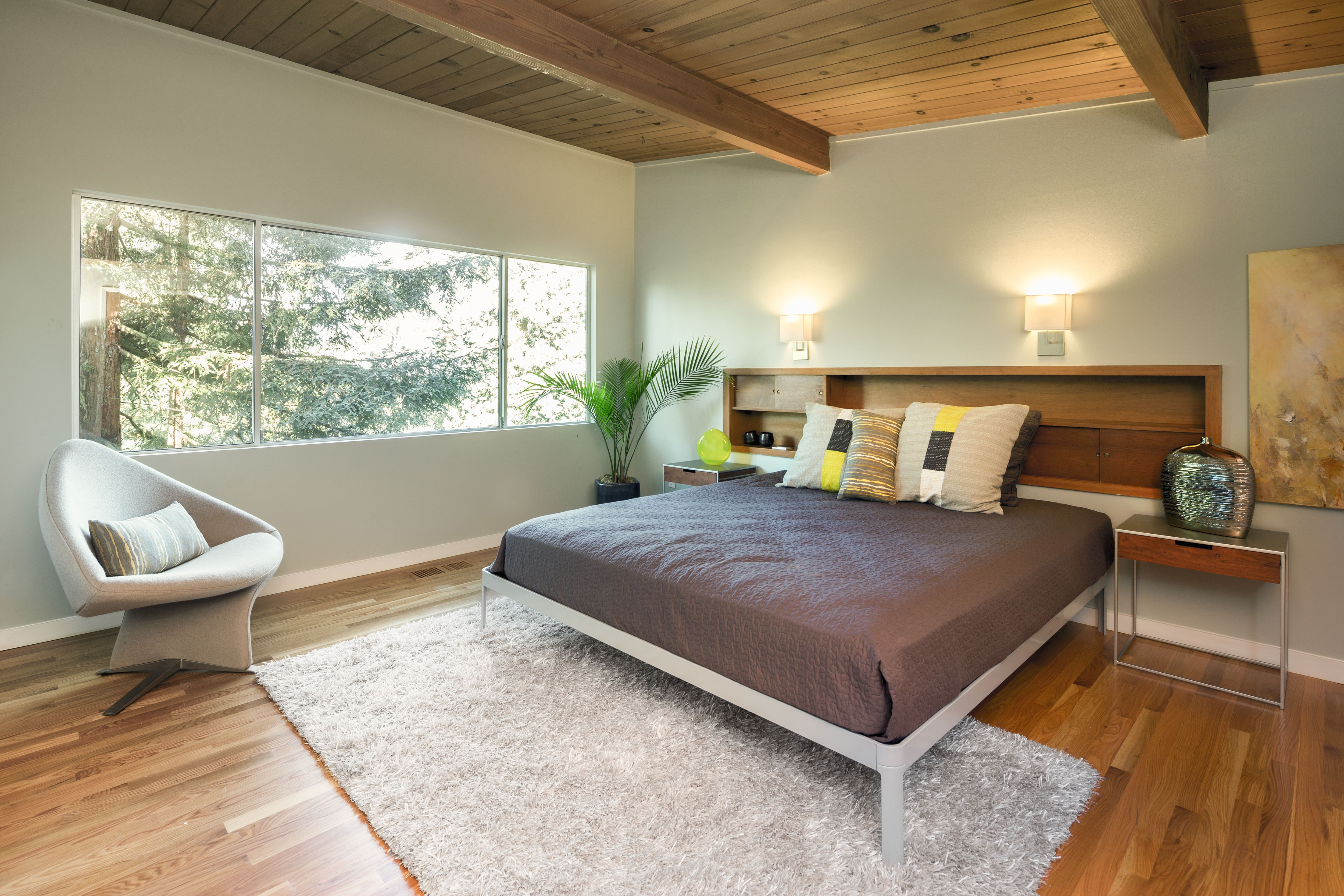 Modern bedroom with wooden walls and ceiling, a bed, chair and area rug