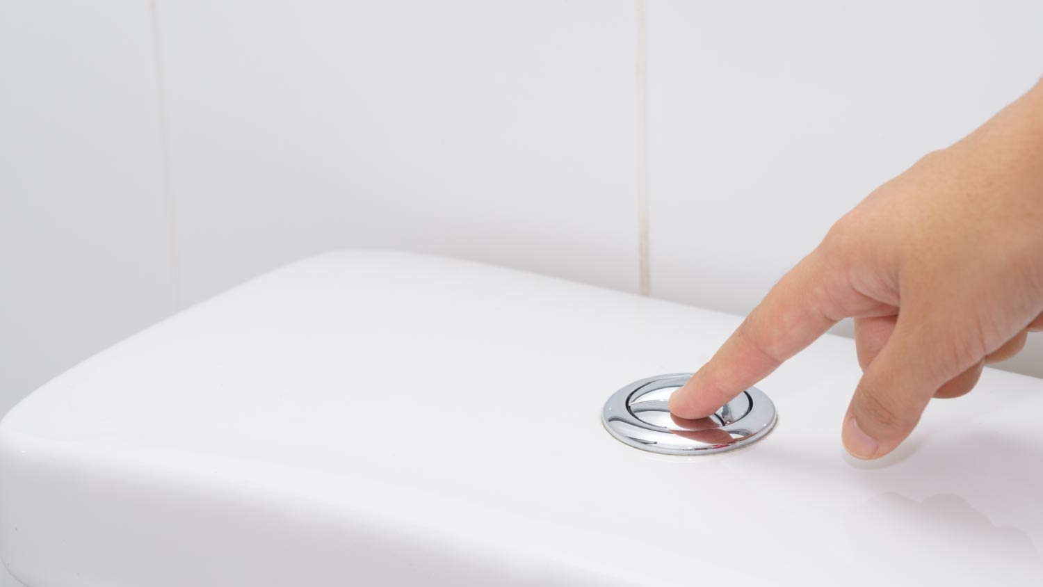 A finger pushing a flush toilet button