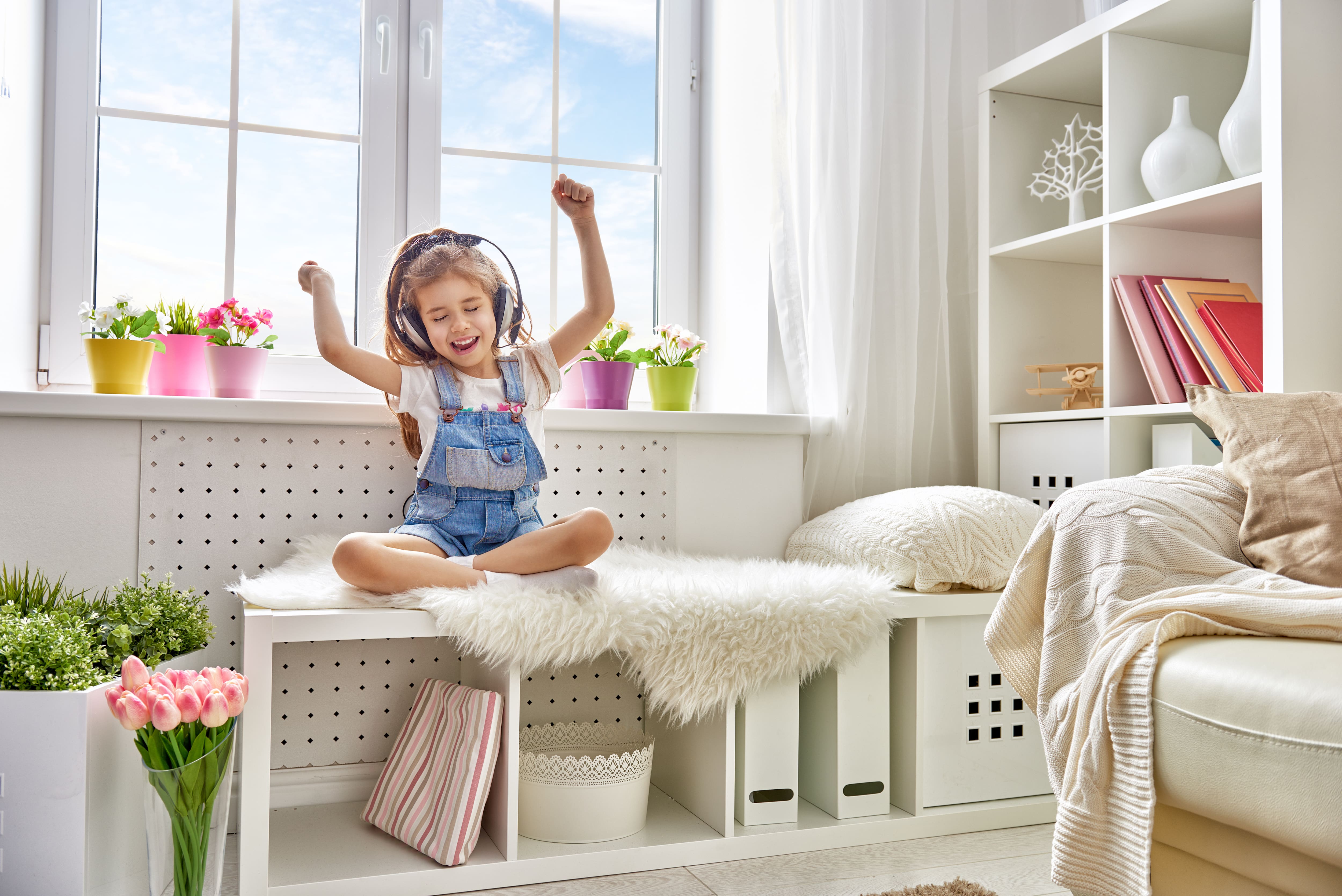A young girl wearing headphones sitting on a shelf bench