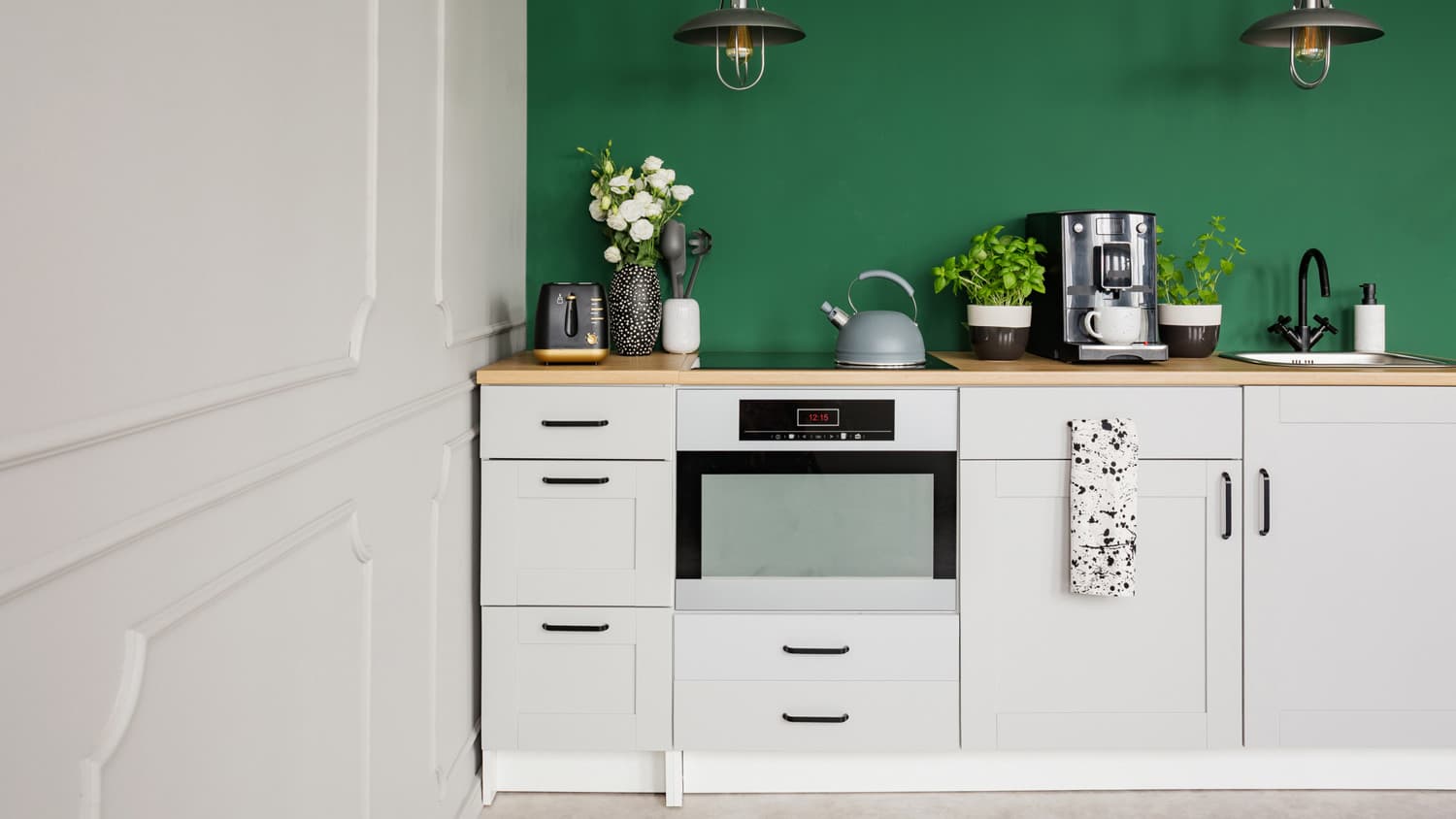 White kitchen cabinets with a wall painted in a vivid green color