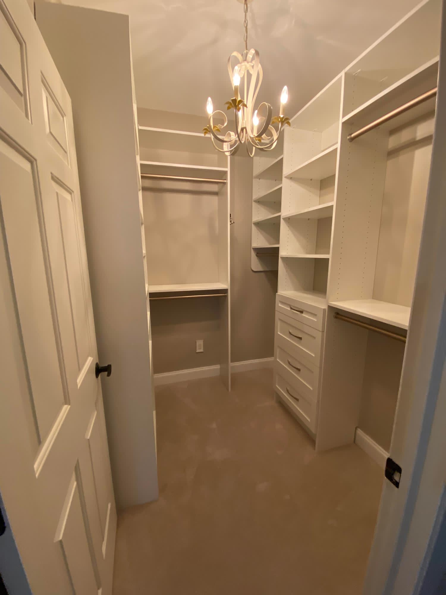 An empty walk-in closet with a hanging chandelier