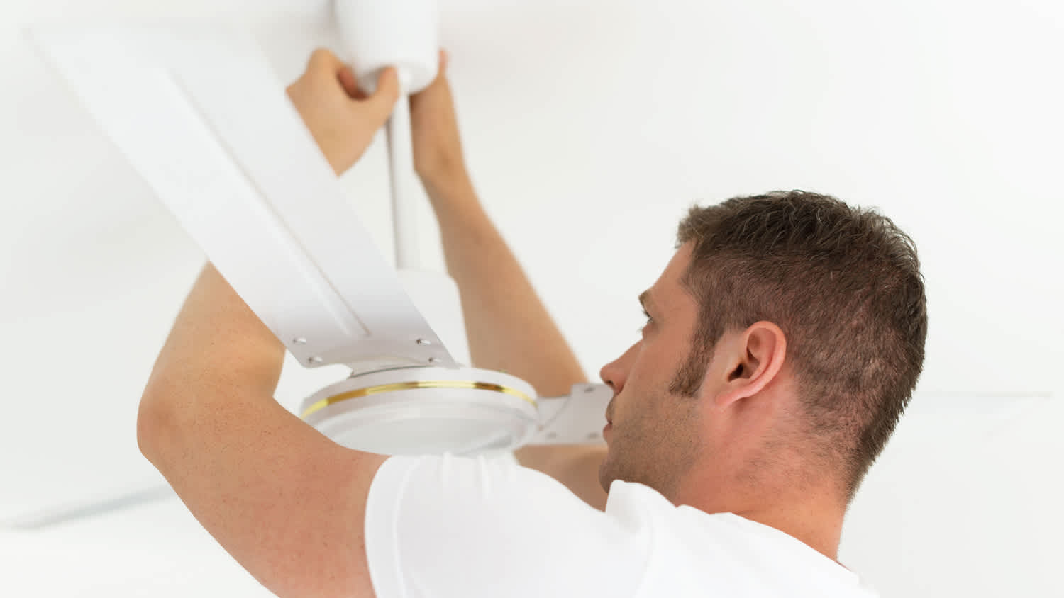 A man repairing a ceiling fan mechanism
