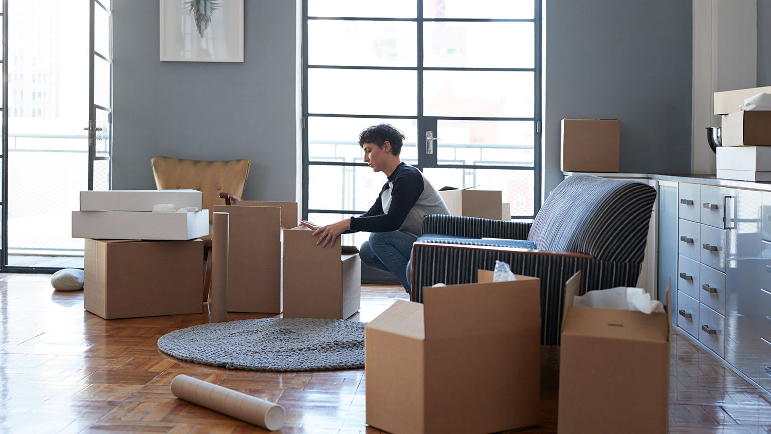 Woman in her apartment packing carboard boxes with her belongings