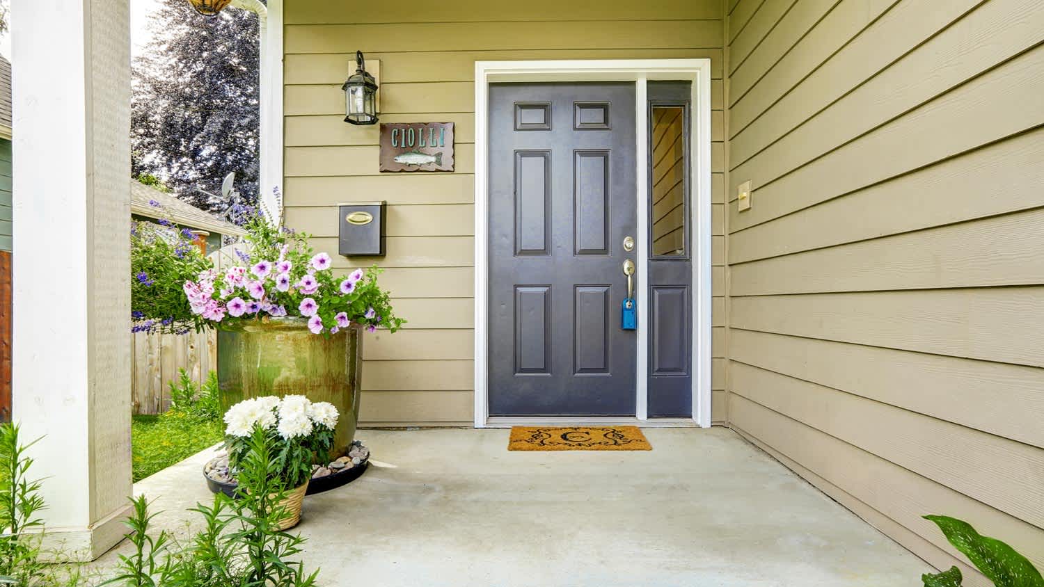 Blue front door of a suburban home surrounded by trees