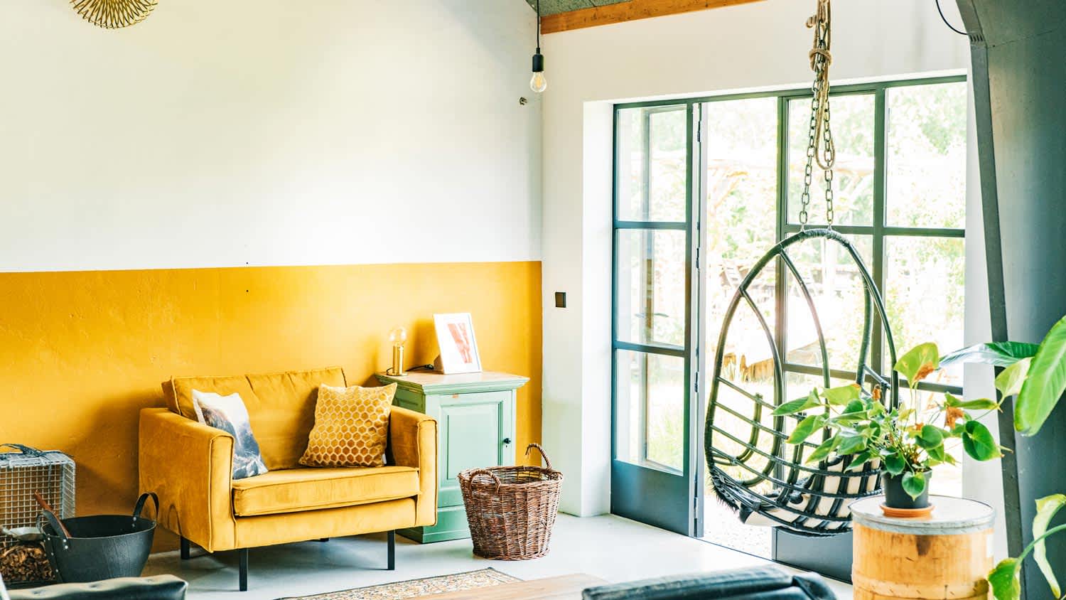A bright boho interior with a mustard wall matching an armchair