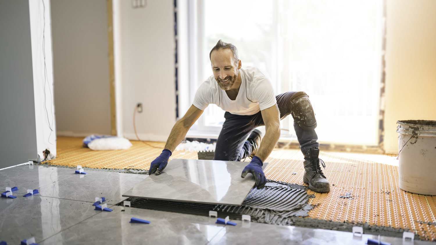 A contractor laying tiles on a new house