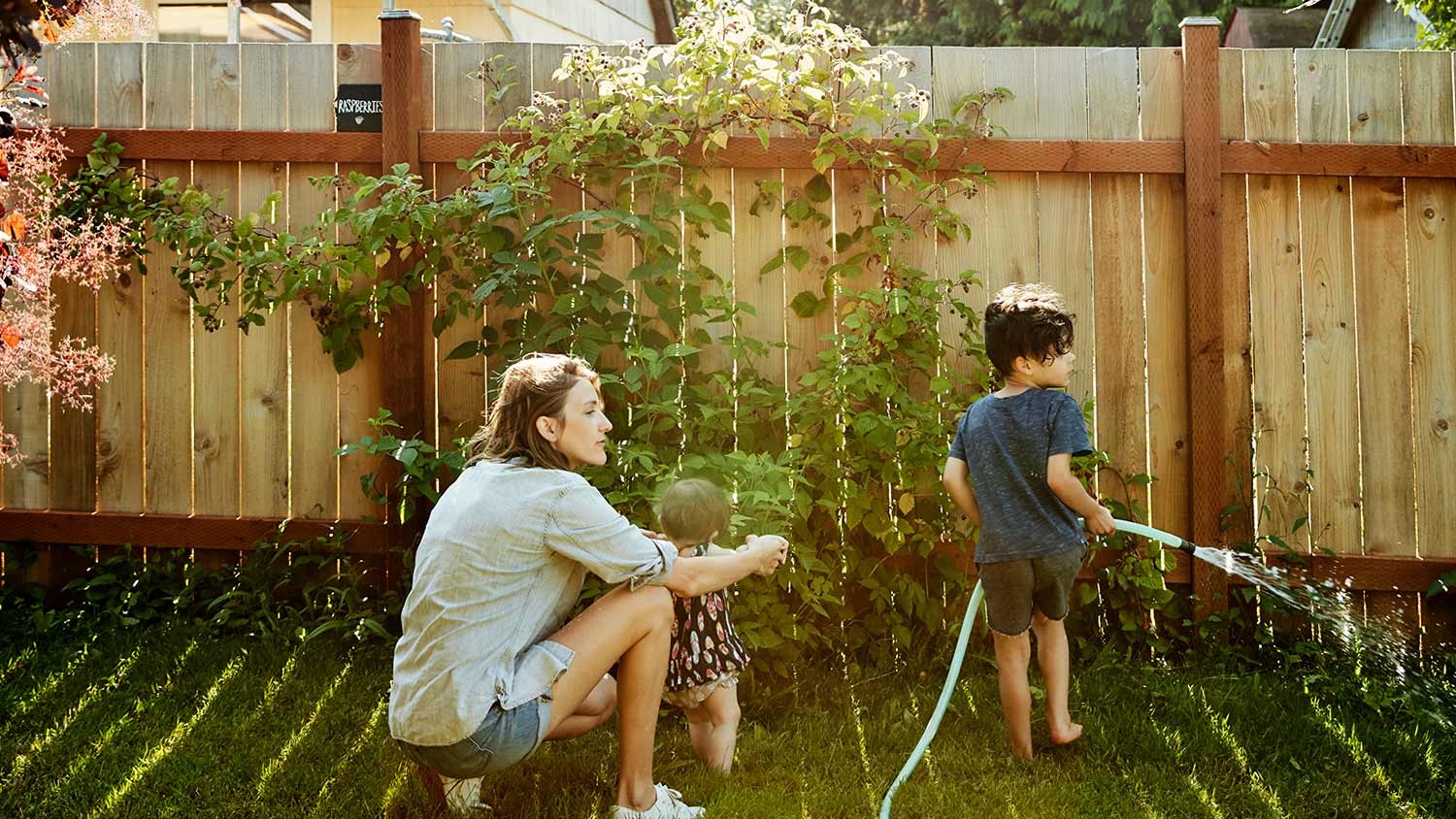 Family watering yard by fence