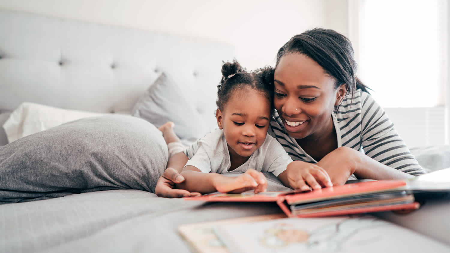mother and daughter reading together in bed