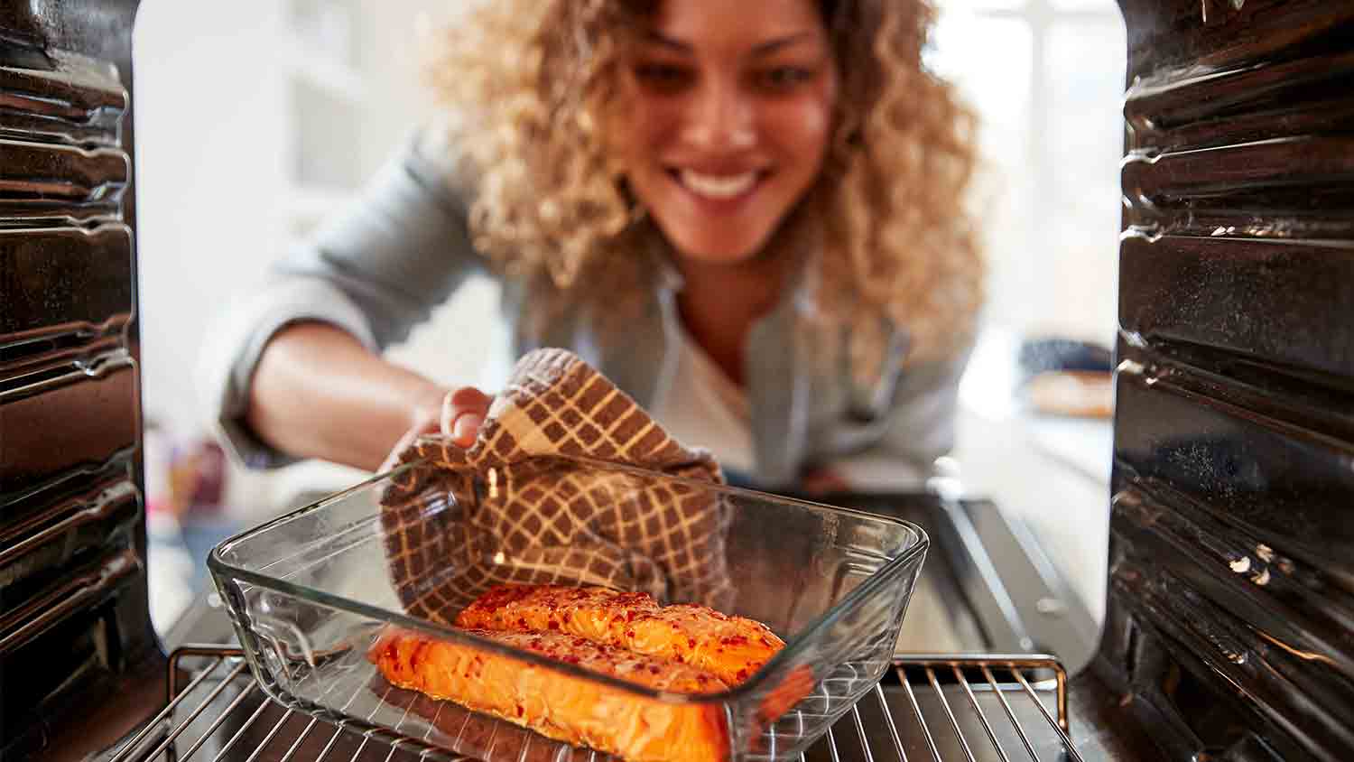 woman taking salmon out the oven