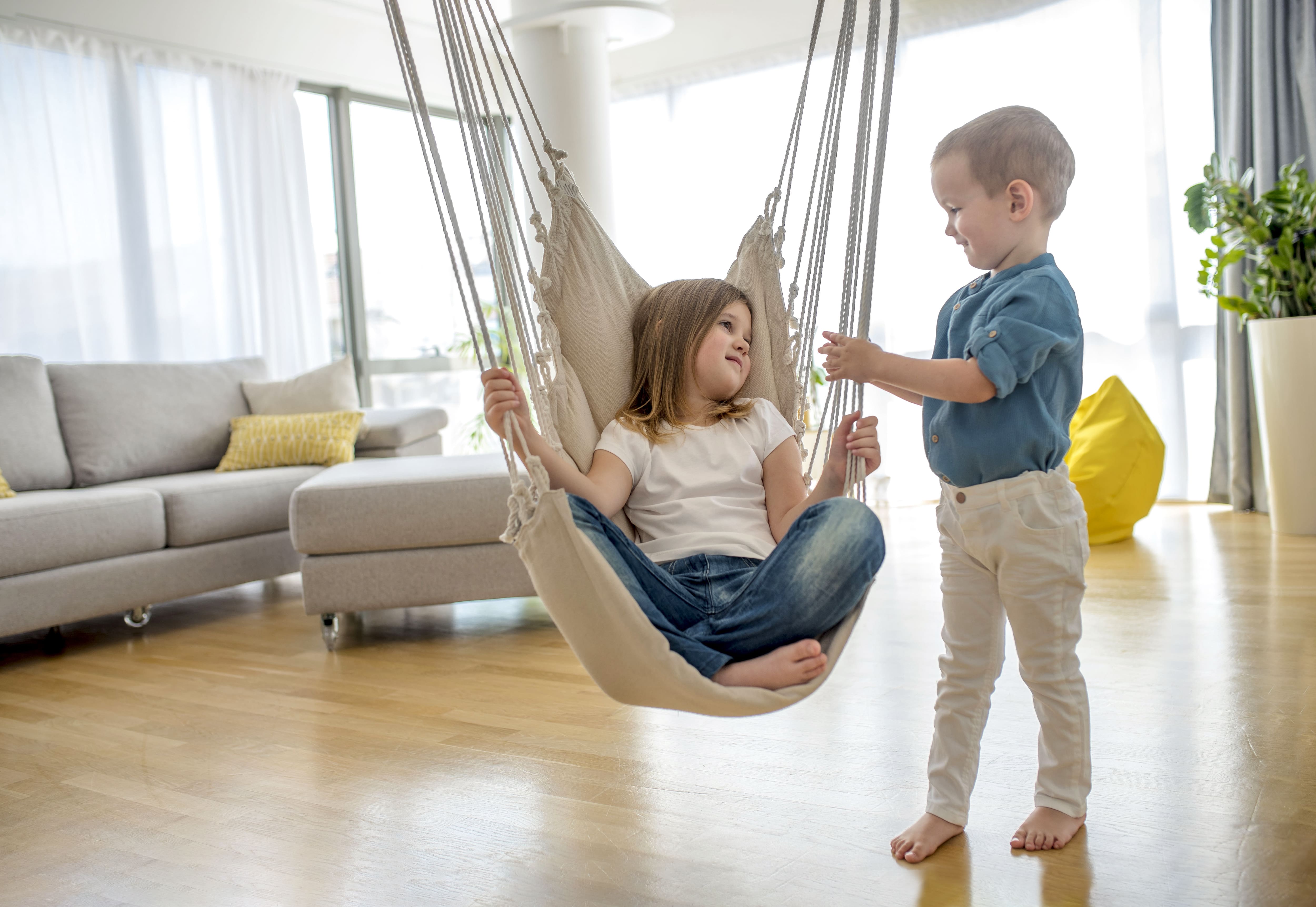 Sister sitting on indoor hanging swing