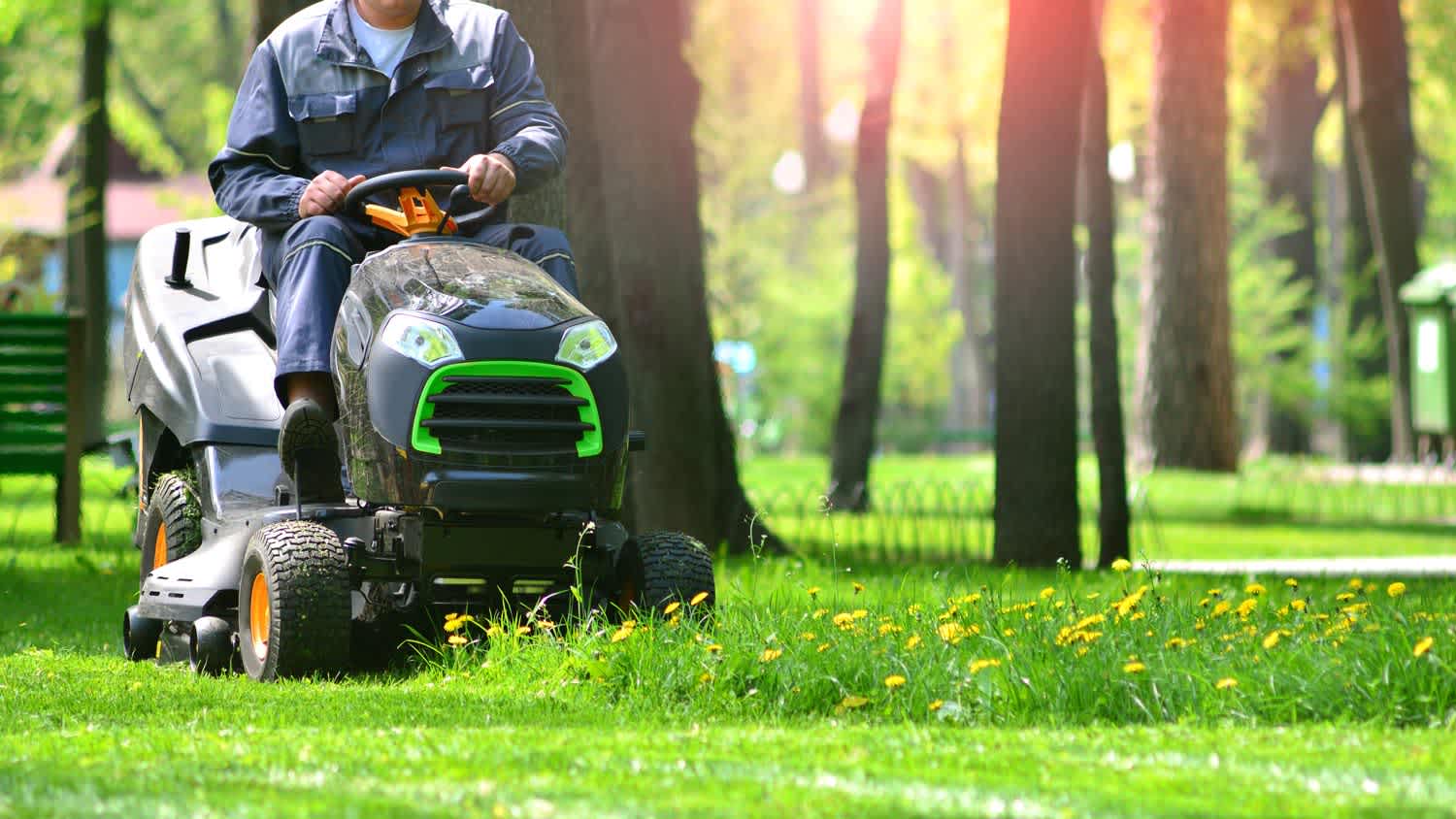 A man using a riding lawn mower in his back yard