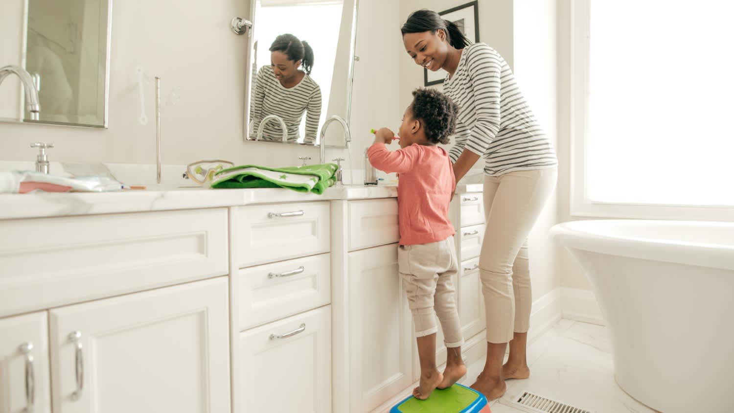 Mother teaching her daughter how to brush her teeth
