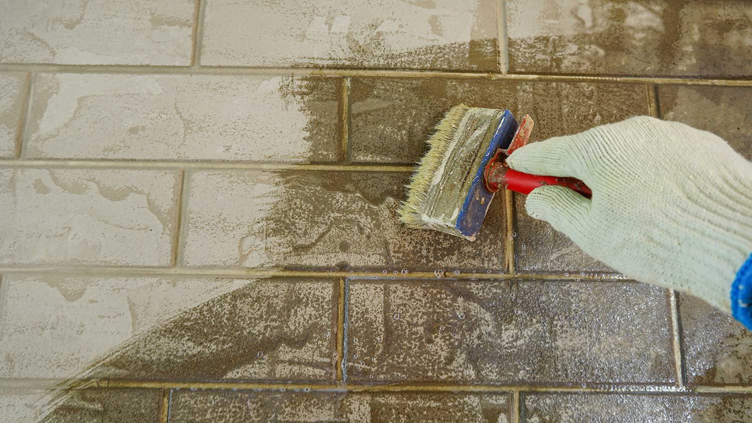 Closeup of a worker applying brick stain with a brush