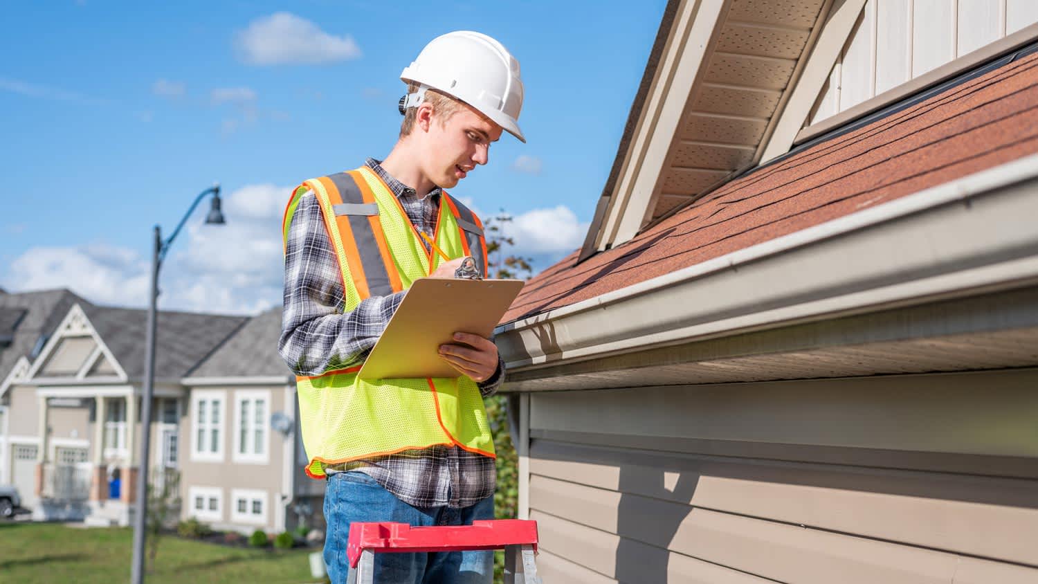 A roof inspector checking a house’s roof for damage
