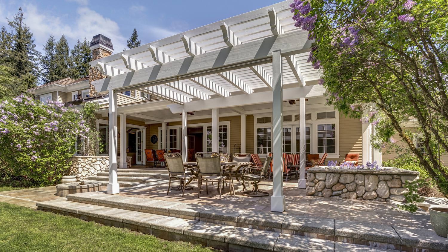 A patio with dining area under a white pergola