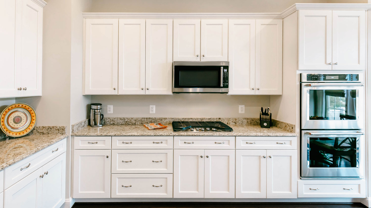 A white cabinetry in a kitchen with granite countertops