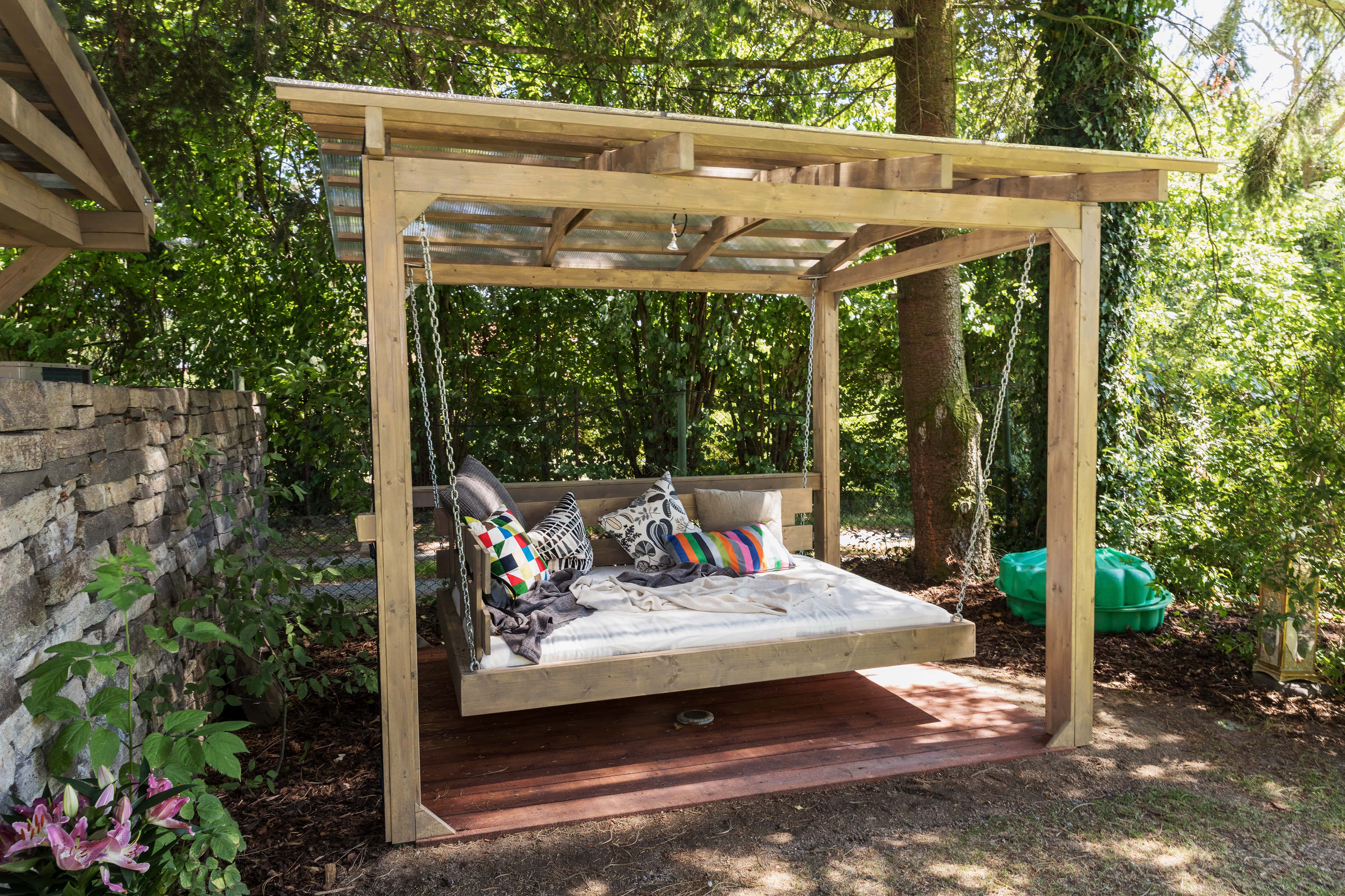 Wooden pergola with roof that has a hanging daybed
