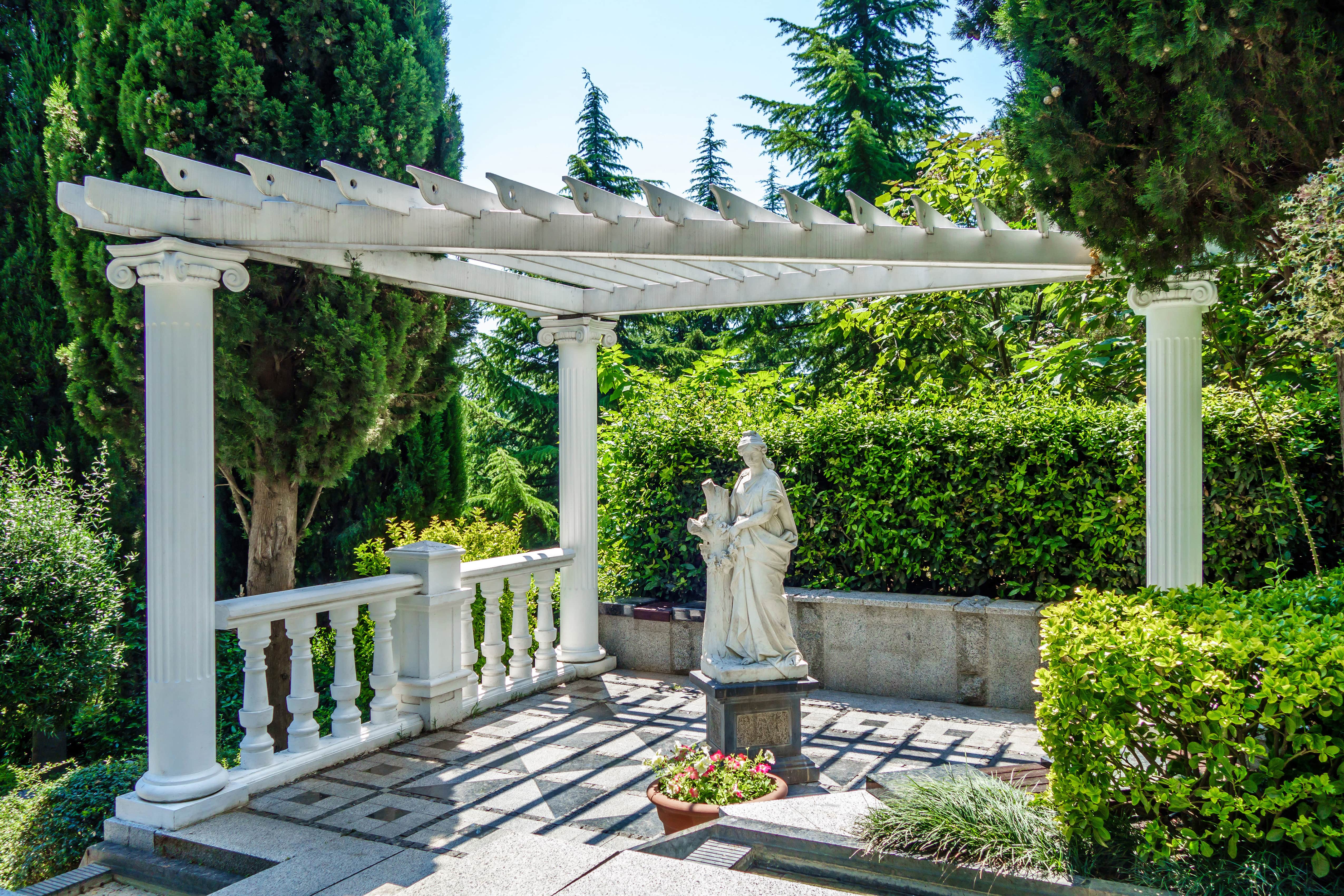 White Grecian pergola with pillars and a statue