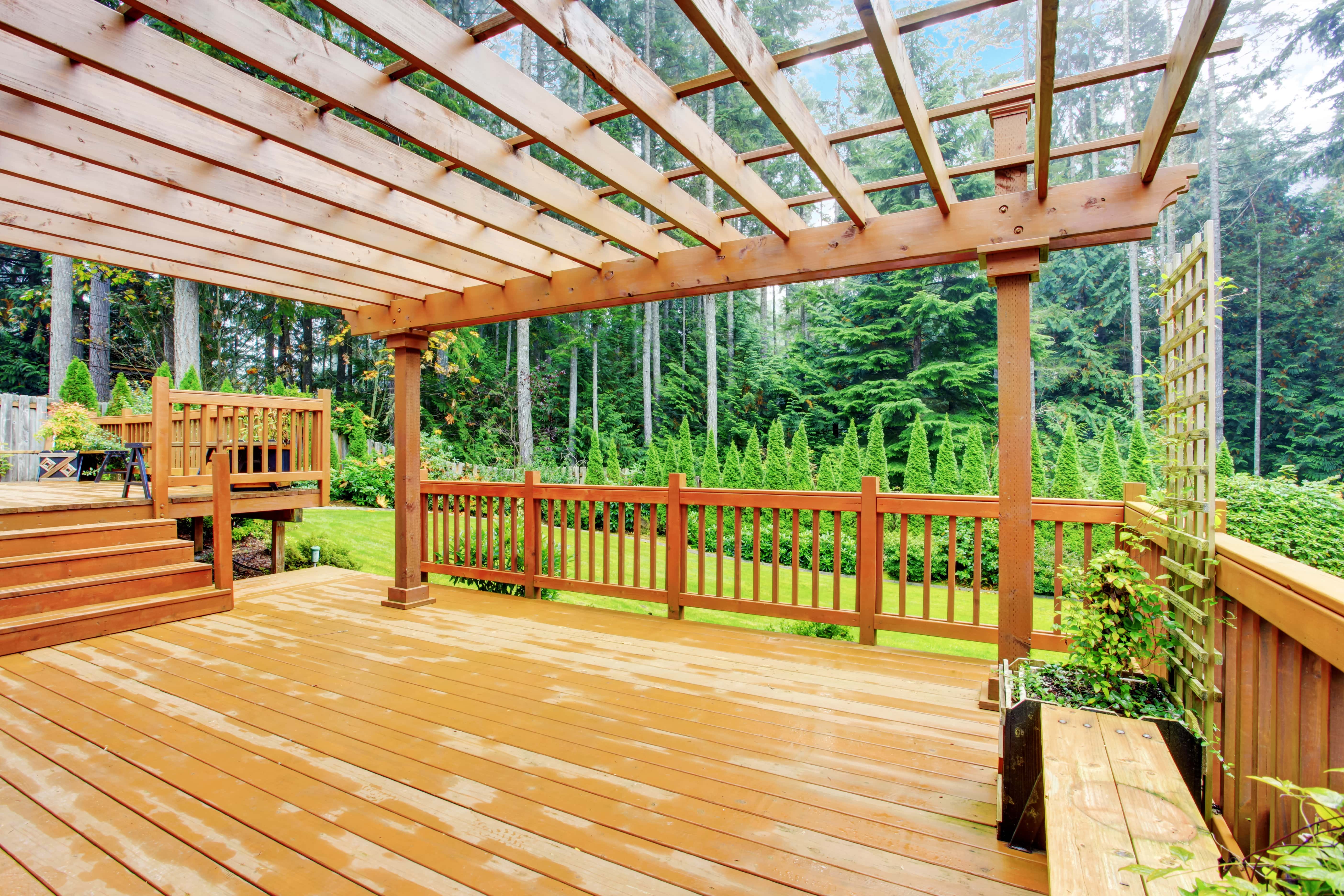 Large deck overlooking a backyard with a wooden pergola