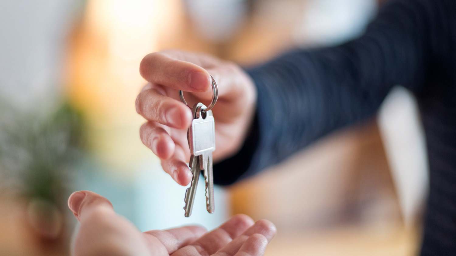 A person handing keys to a neighbor