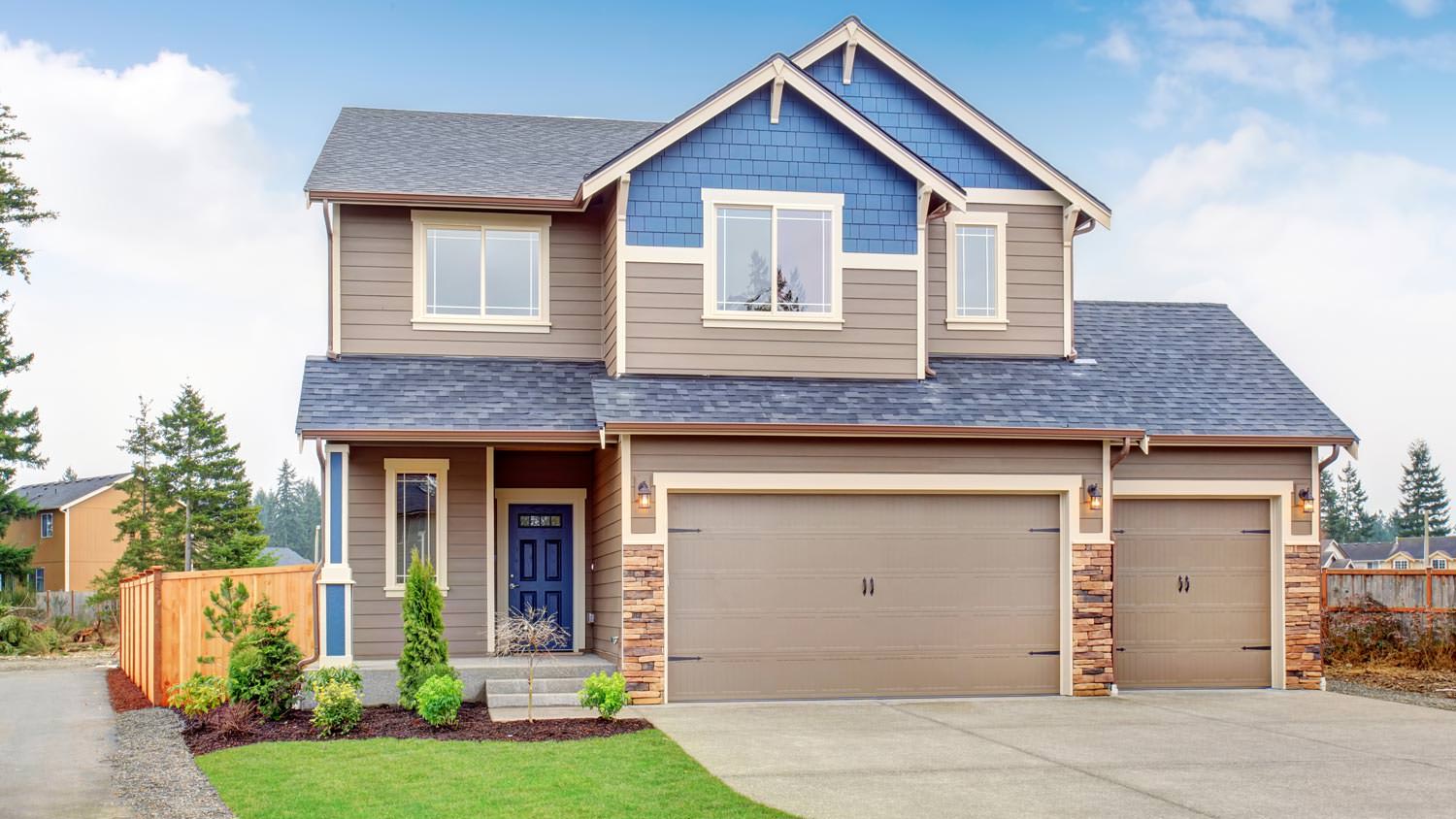 A two story house with a concrete driveway leading to a garage