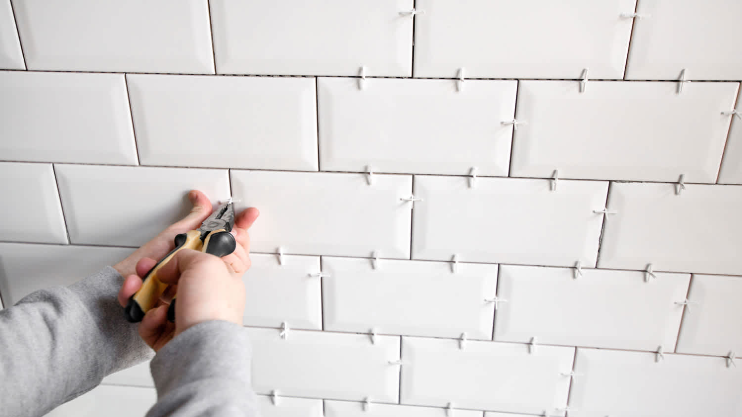 A worker installing new ceramic tiles on the wall of a bathroom