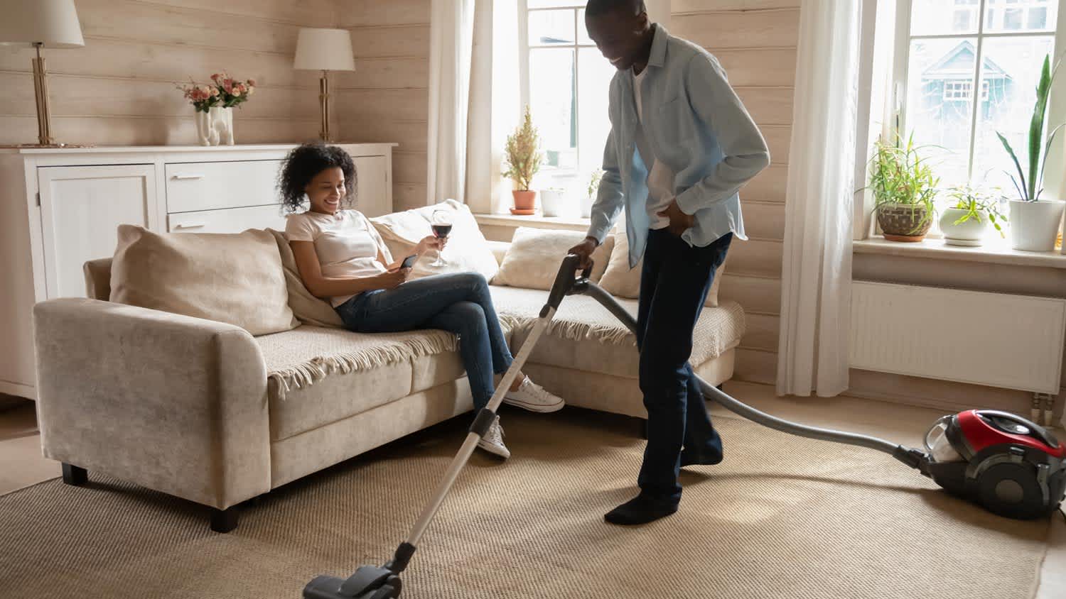 A man cleaning the carpet with a vacuum