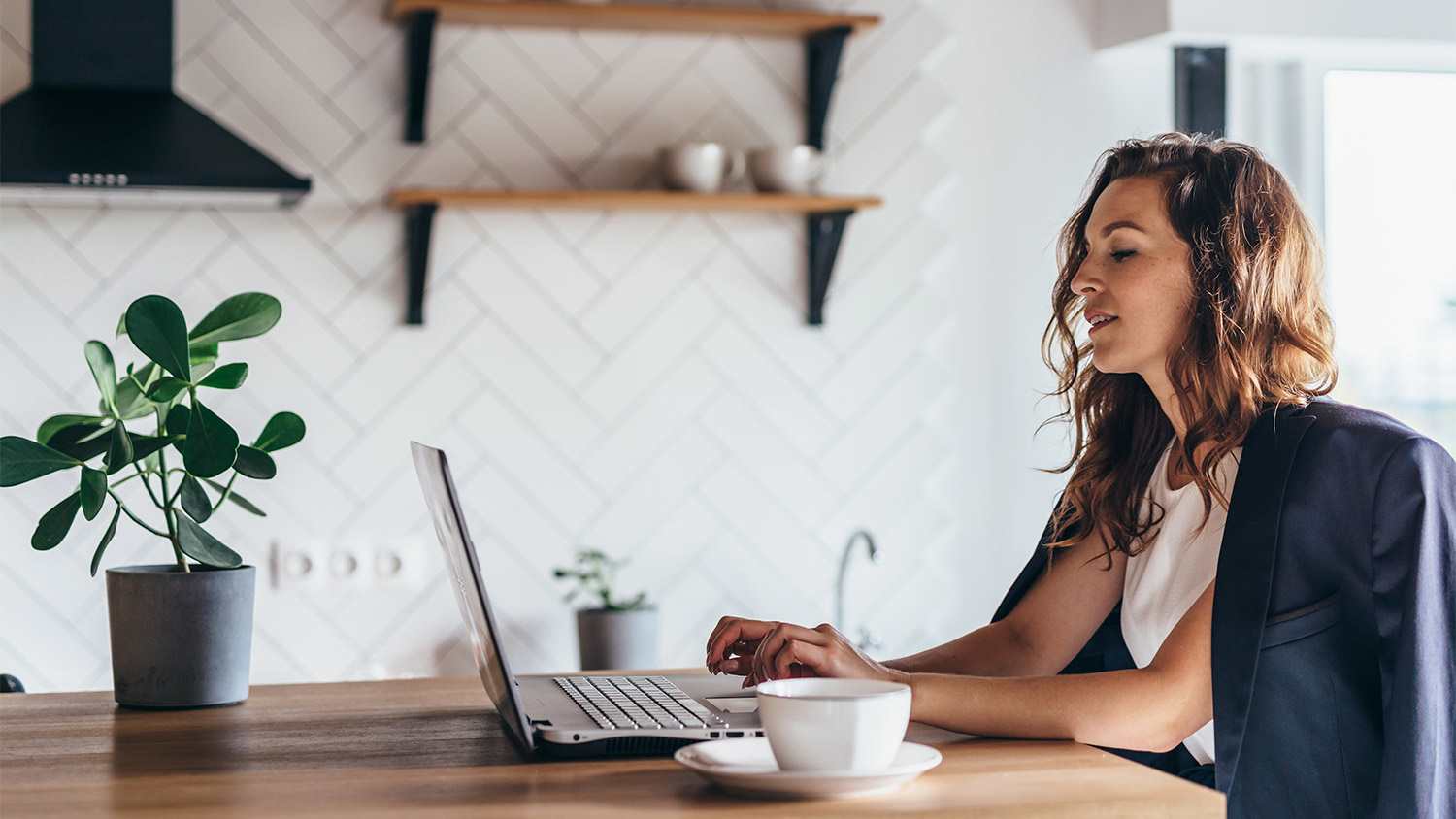 Woman home desk laptop mug plant