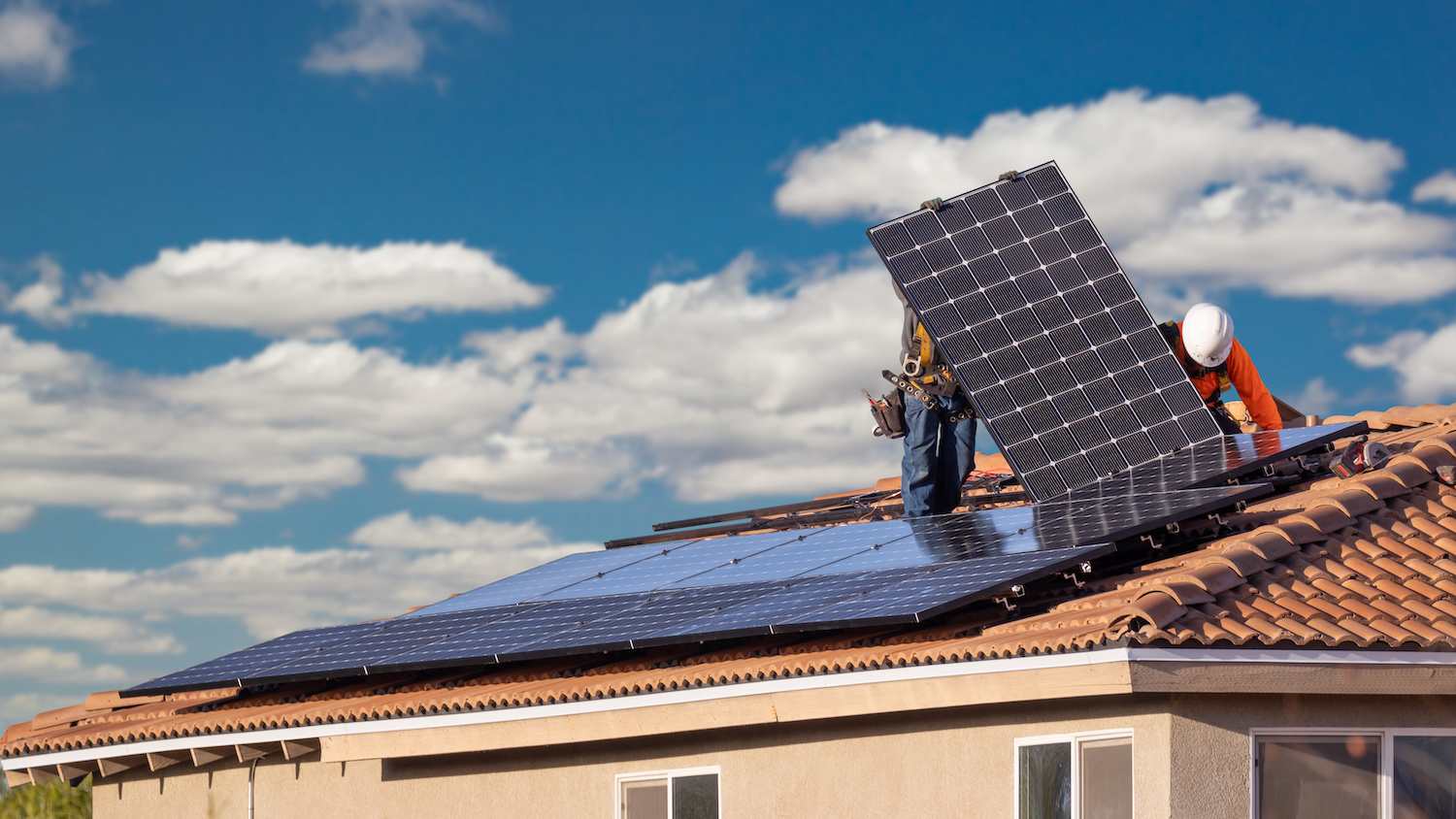 Workers installing solar panels on a roof