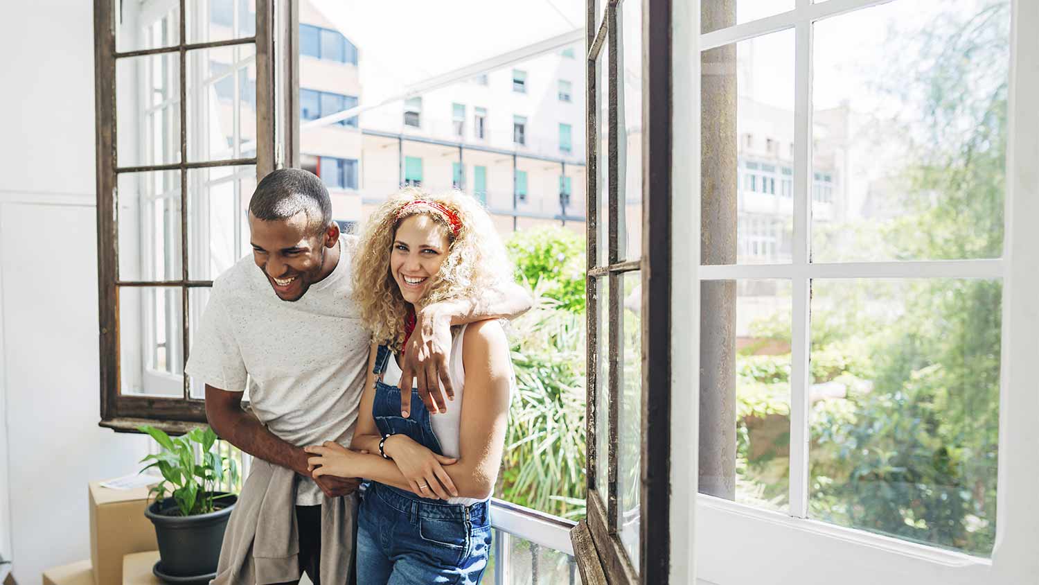 Couple smiles near open windows.