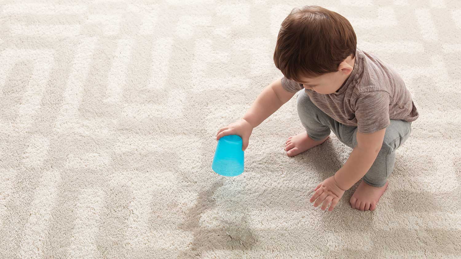 Toddler boy spilling water on the carpet