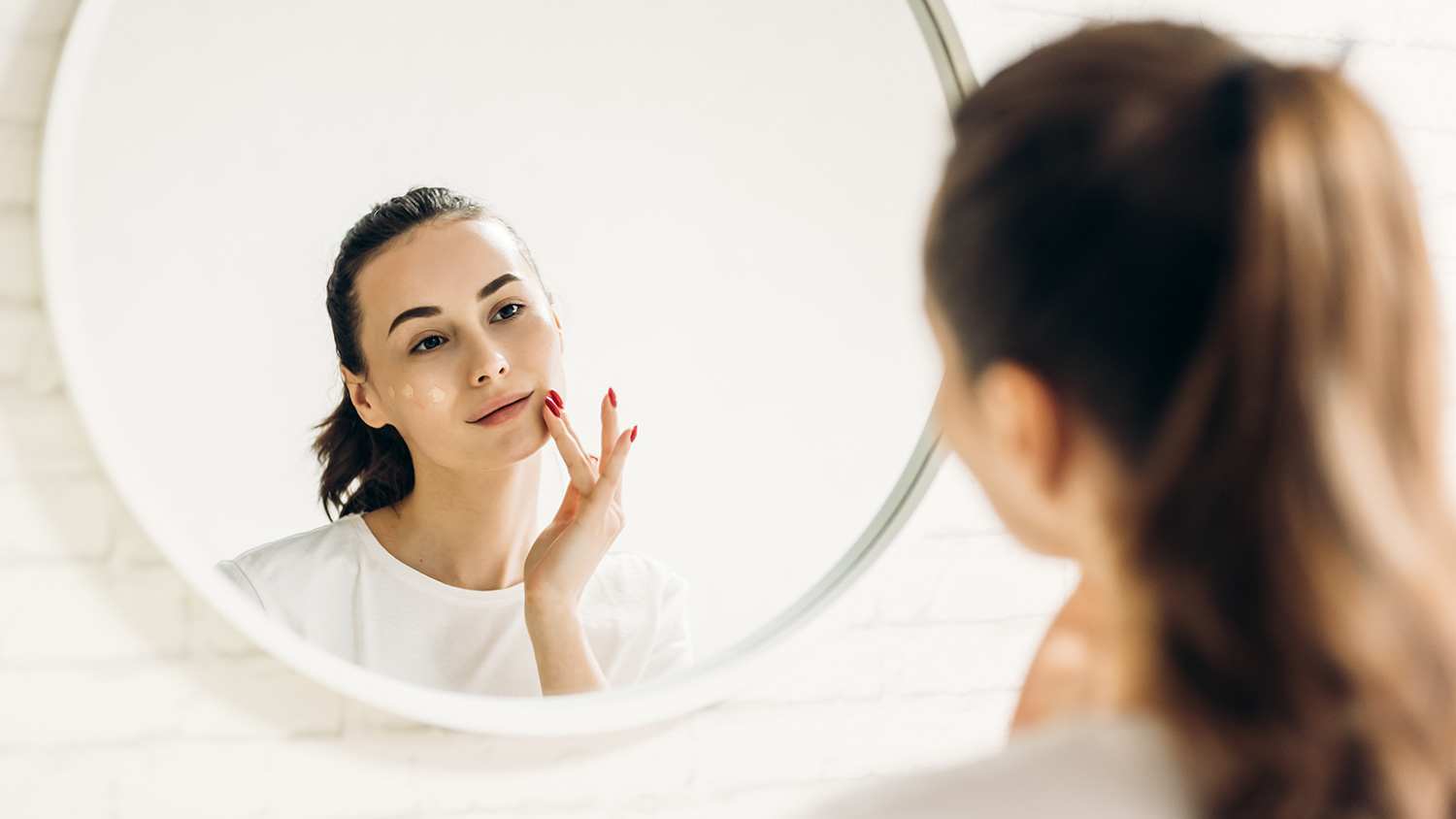 Woman applying makeup in front of the mirror