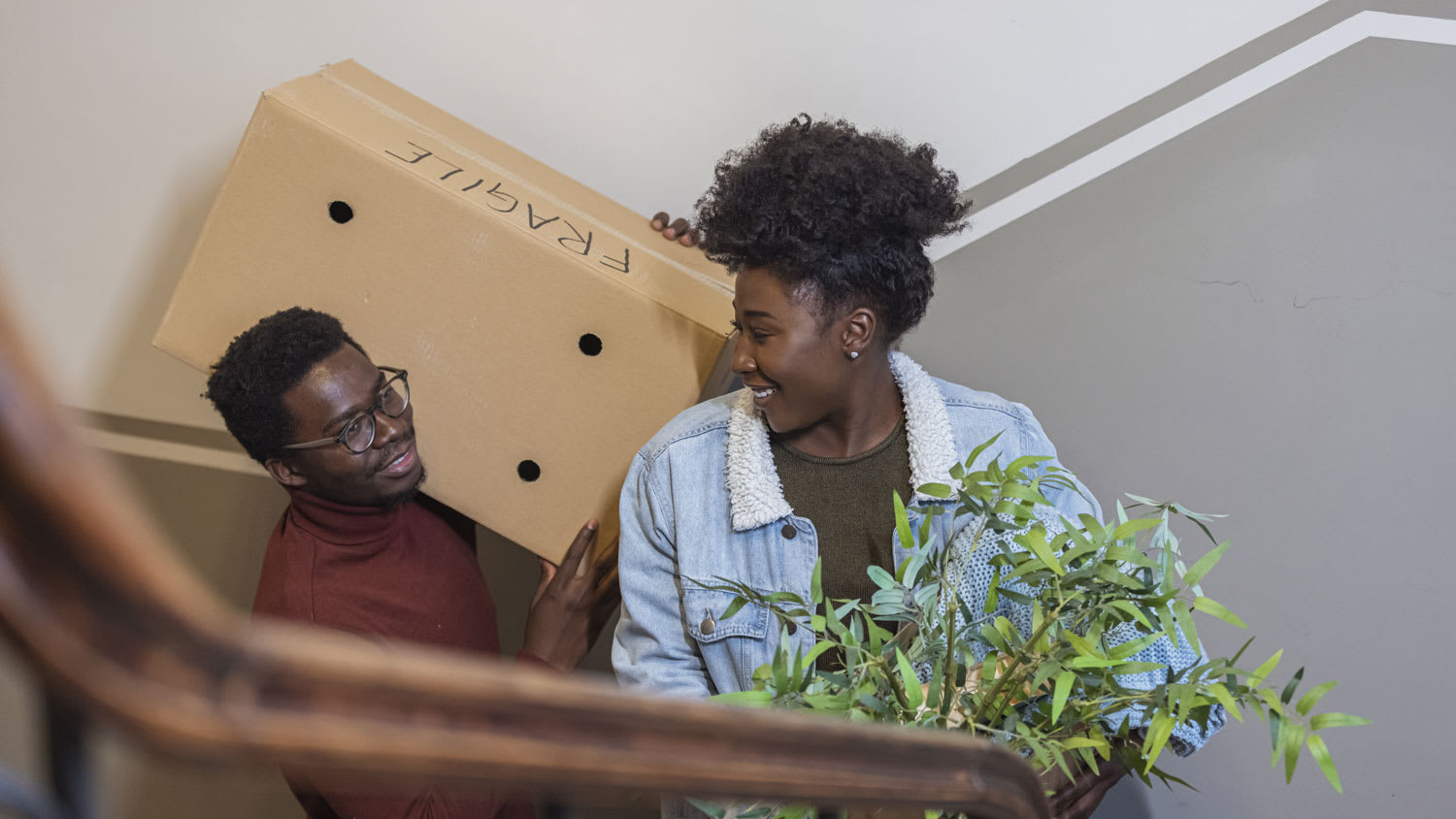 A couple caring moving box in the staircase