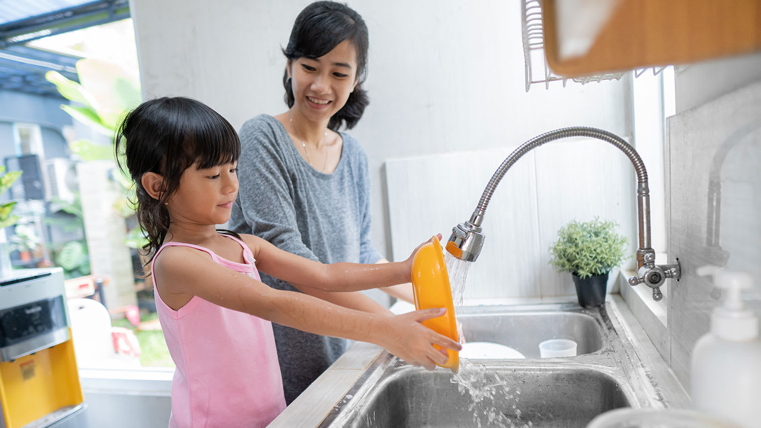 Girl helping mom washing dishes